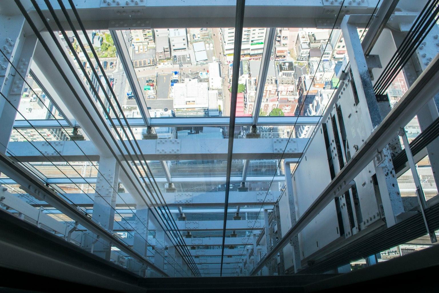 View looking down through glass elevator showcasing urban landscape