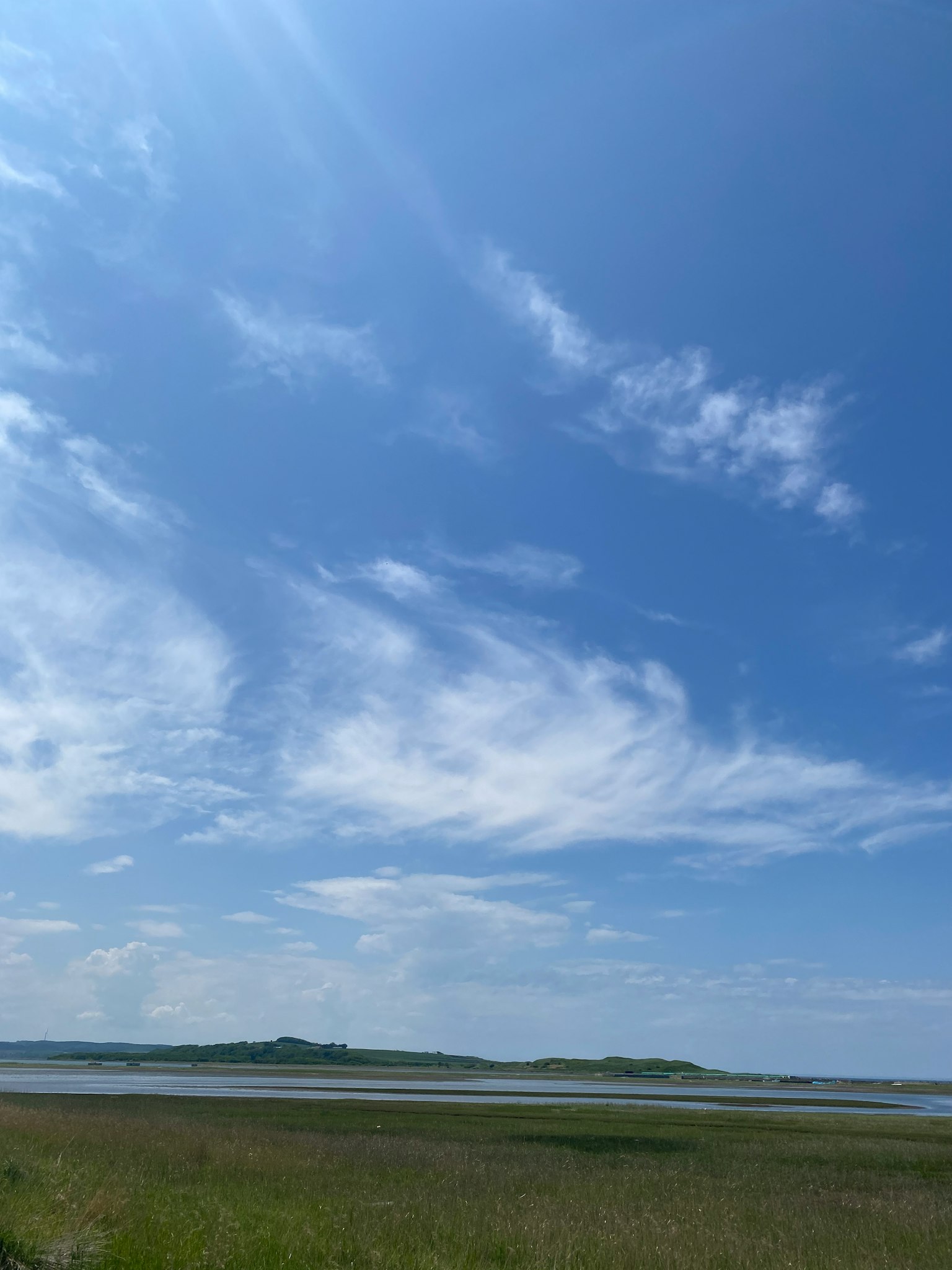 Un paesaggio con cielo blu nuvole bianche erba verde e isole lontane