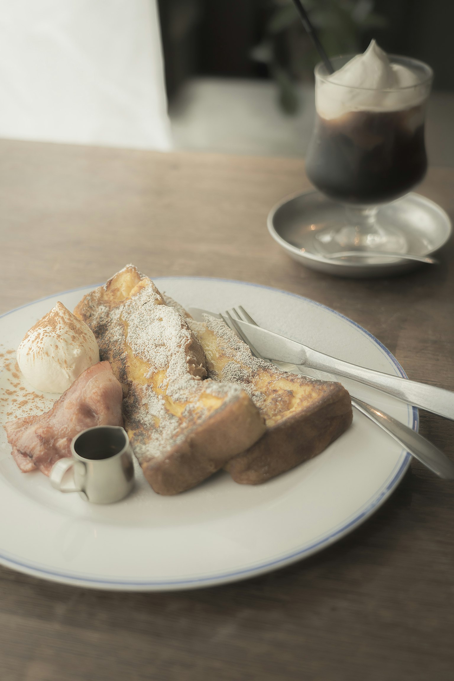 Delicious French toast with ice cream and a small syrup container on a wooden table