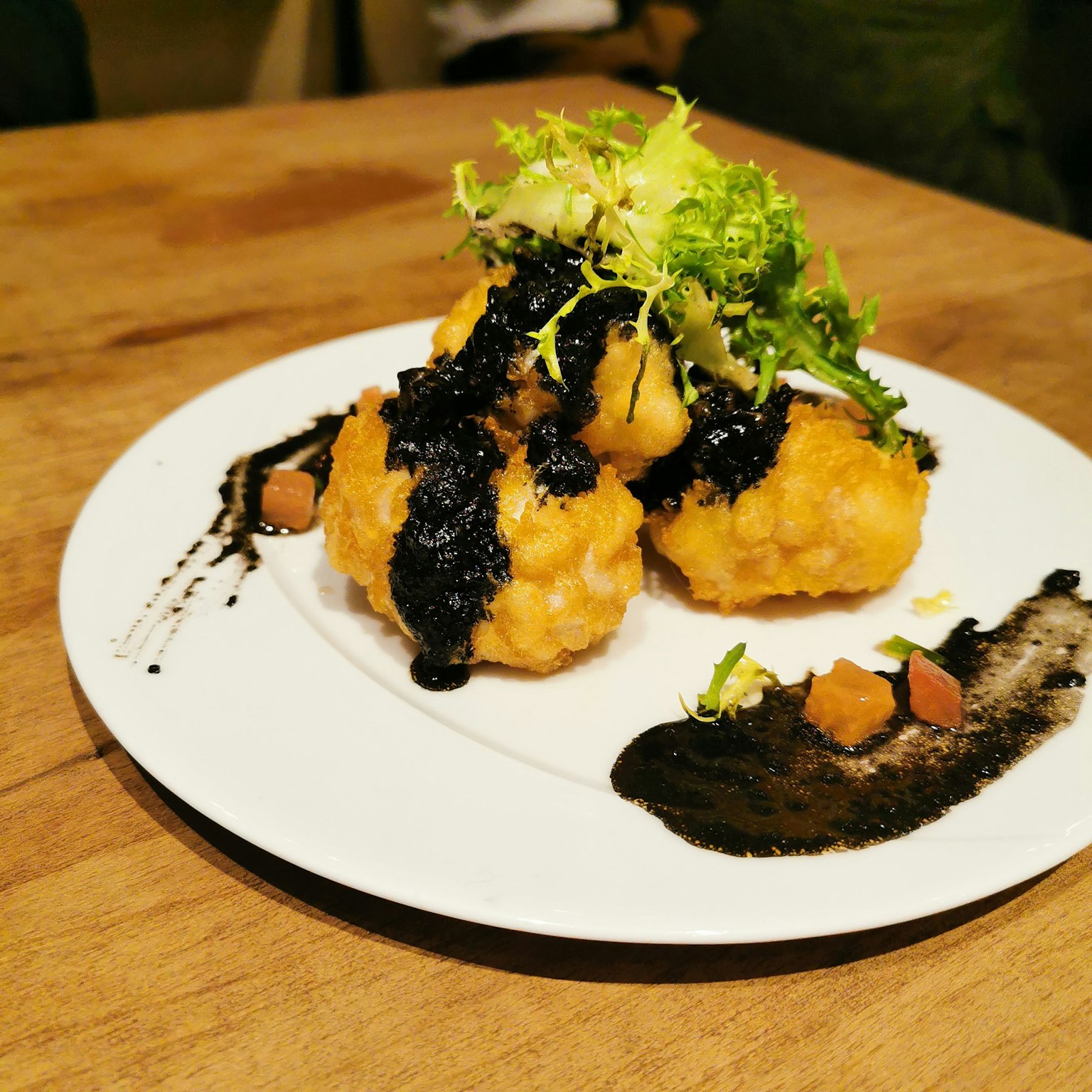 炸菜肴搭配黑色酱汁和蔬菜装饰