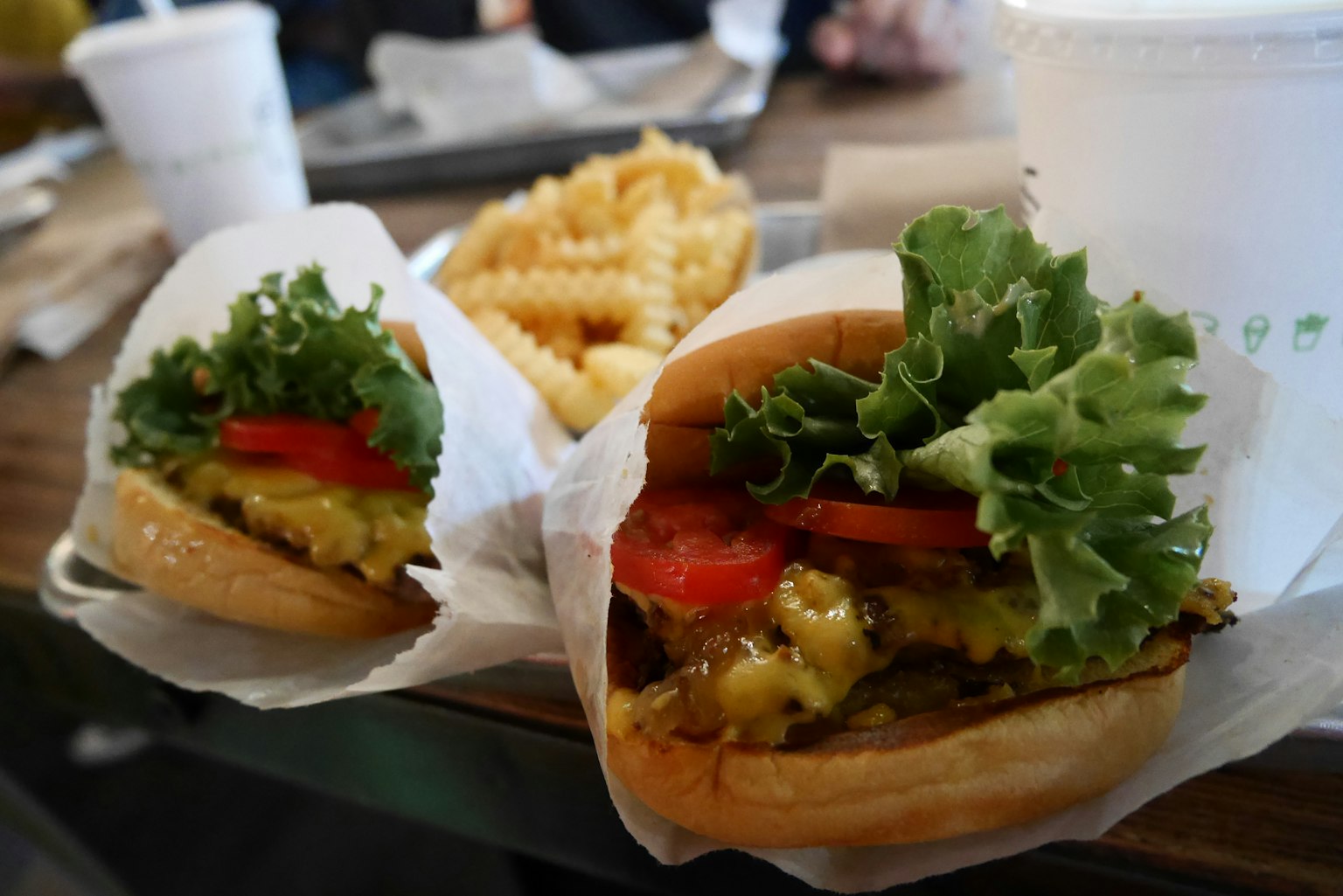 Deux hamburgers avec laitue et tomate accompagnés d'une assiette de frites ondulées