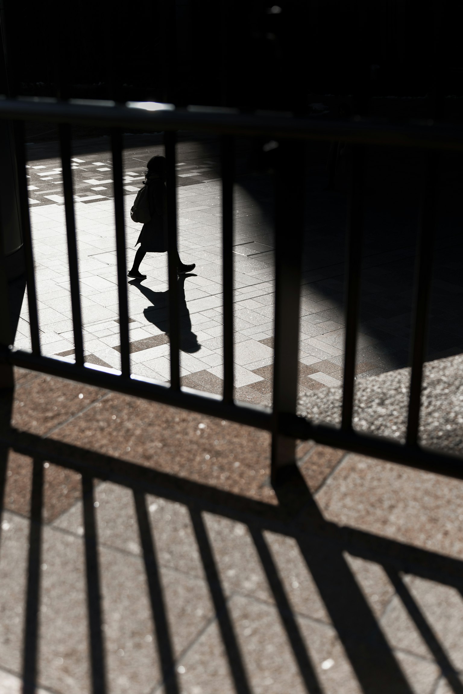 Silhouette d'une personne marchant à travers des ombres avec des ombres de clôture