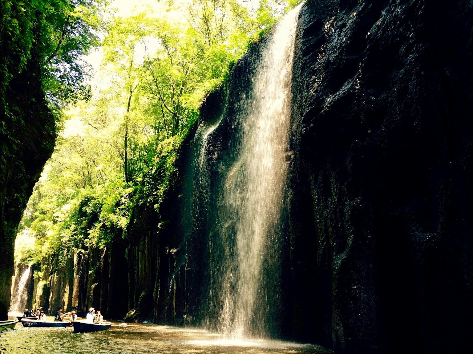 Waterfall cascading down rocky cliffs in a lush green canyon
