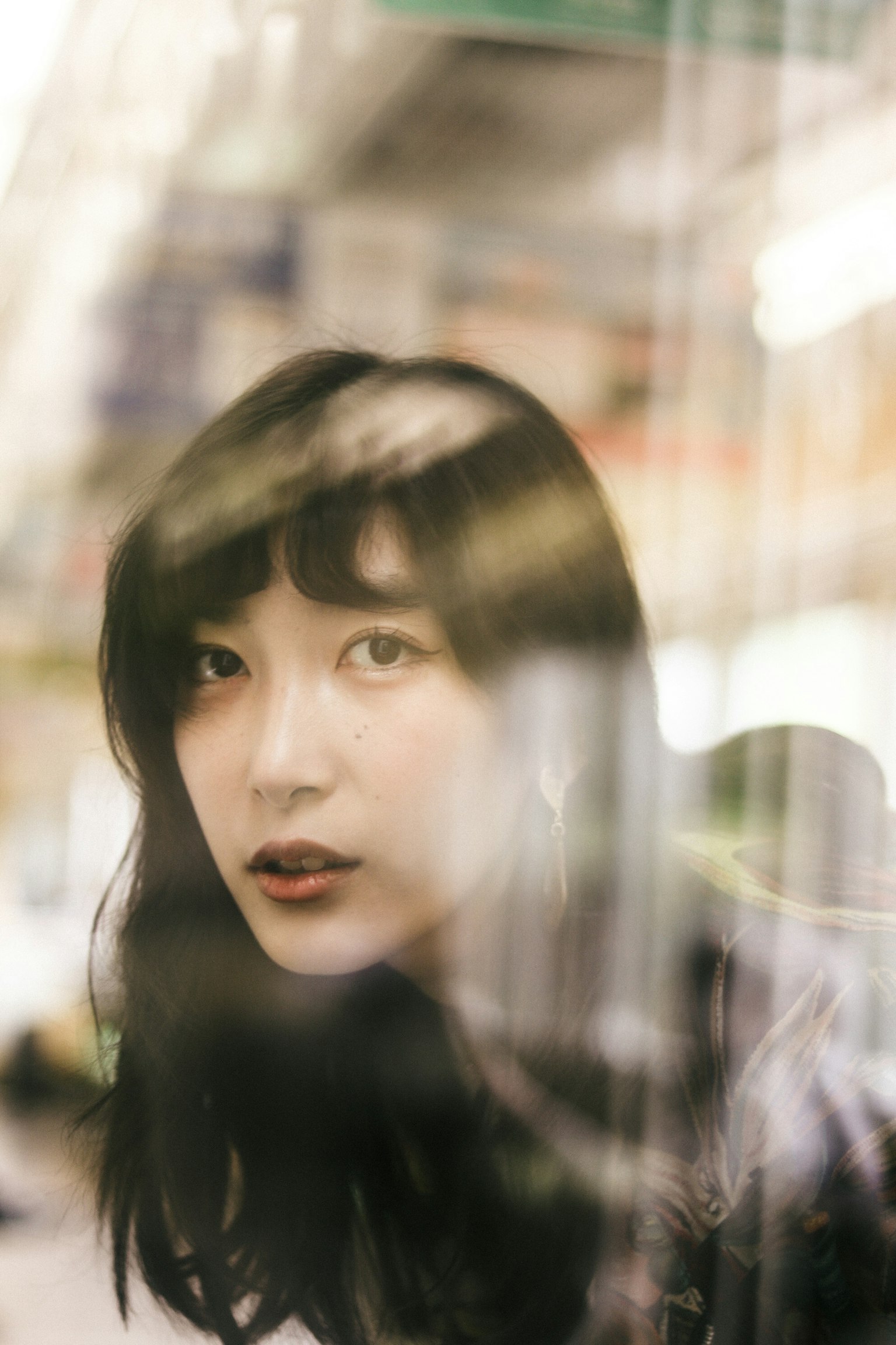 창을 통해 보이는 여성의 초상 그녀의 검은 머리와 표정이 인상적이다