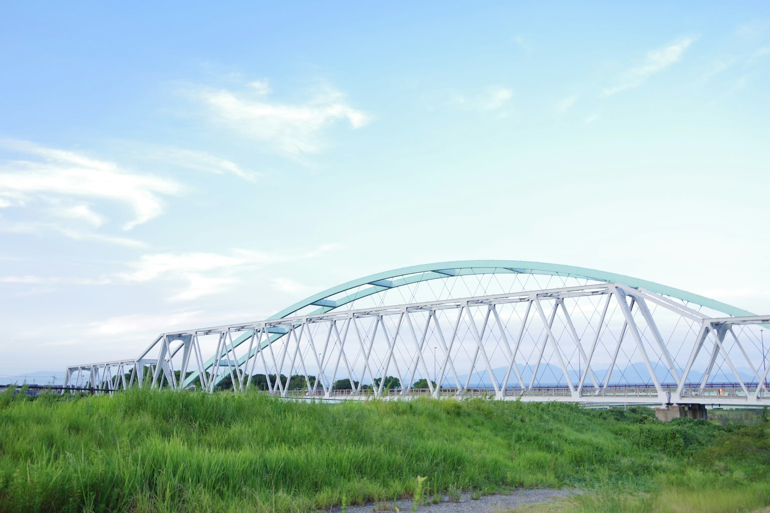 Weißer Bogenbrücke über grünem Gras unter blauem Himmel