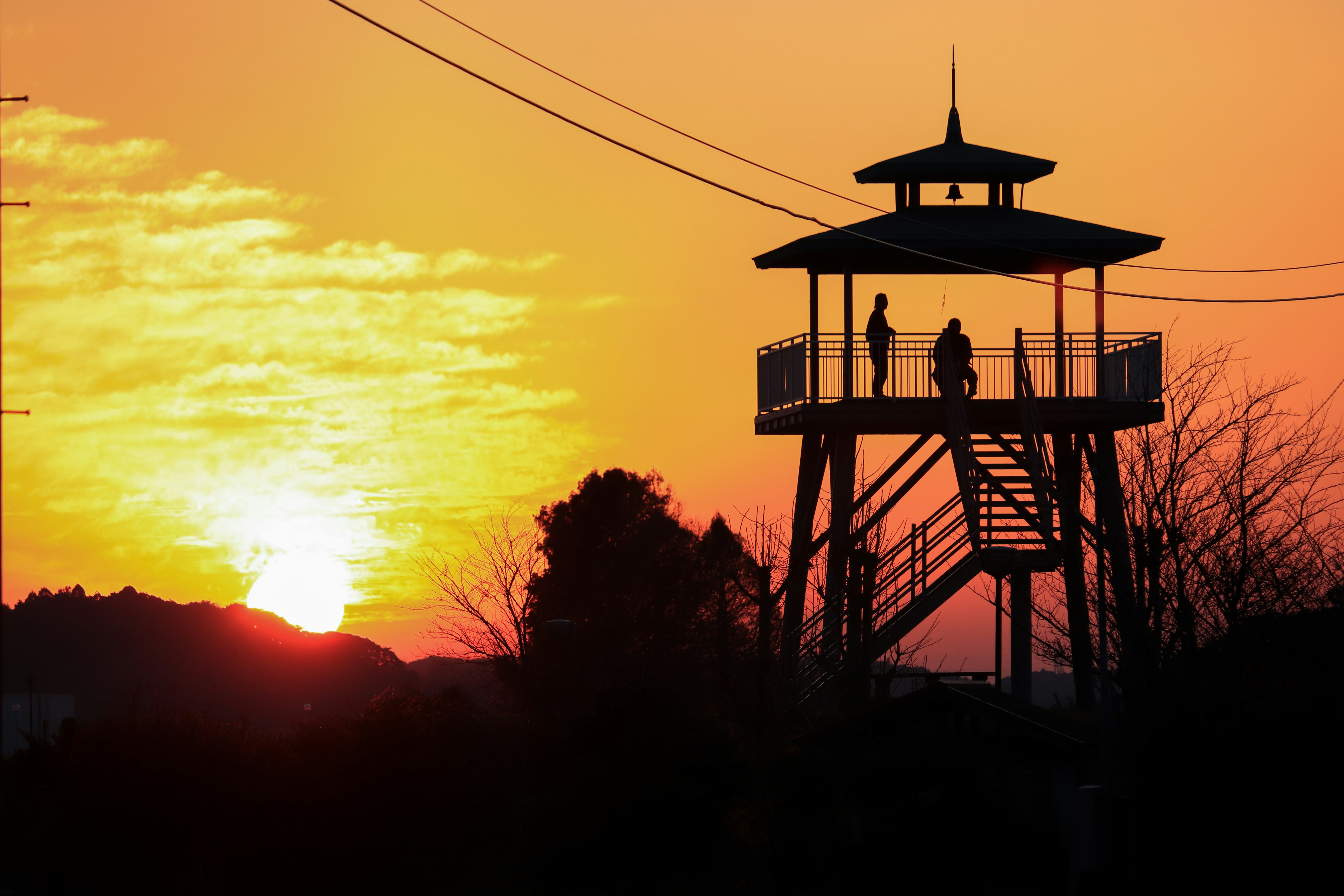 tour de guet éclairée par le coucher du soleil avec silhouettes de personnes