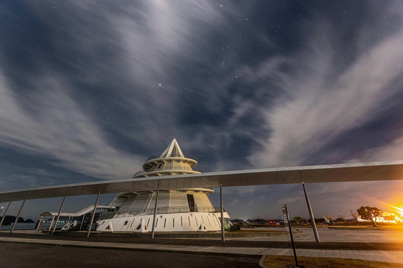 Un bâtiment blanc sous un ciel nocturne avec des nuages