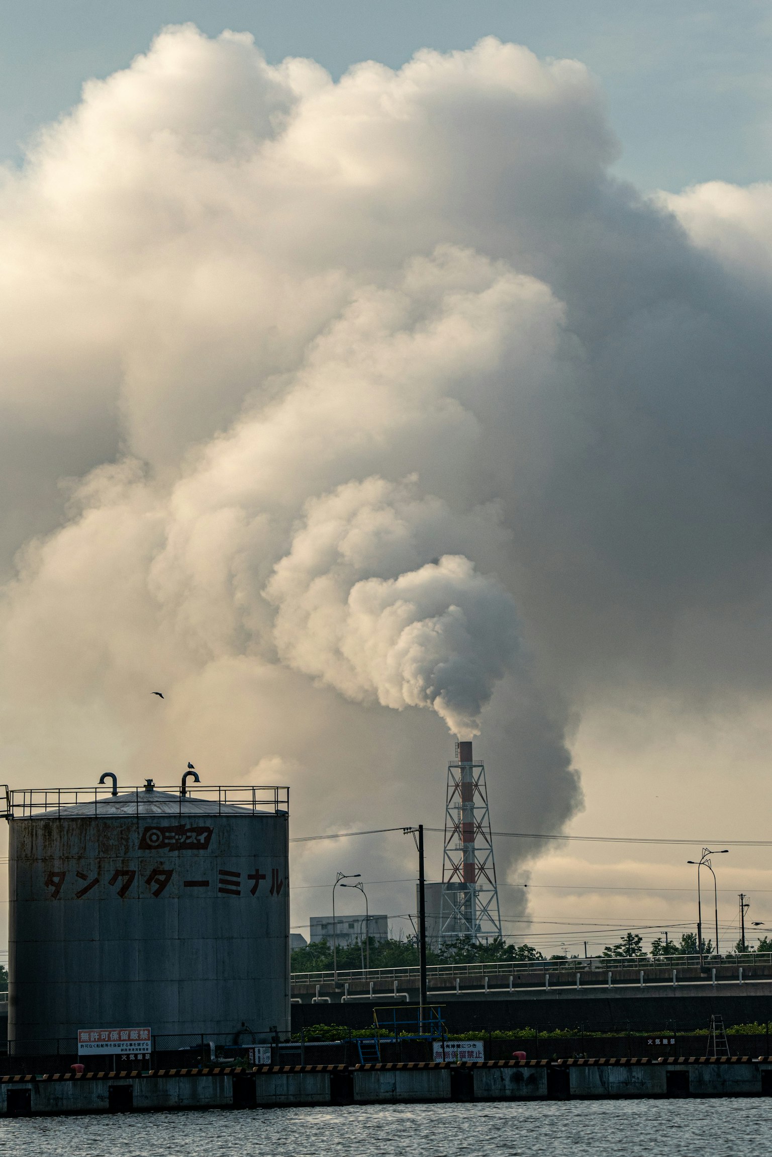 Una fabbrica che emette fumi nel cielo con grandi nuvole