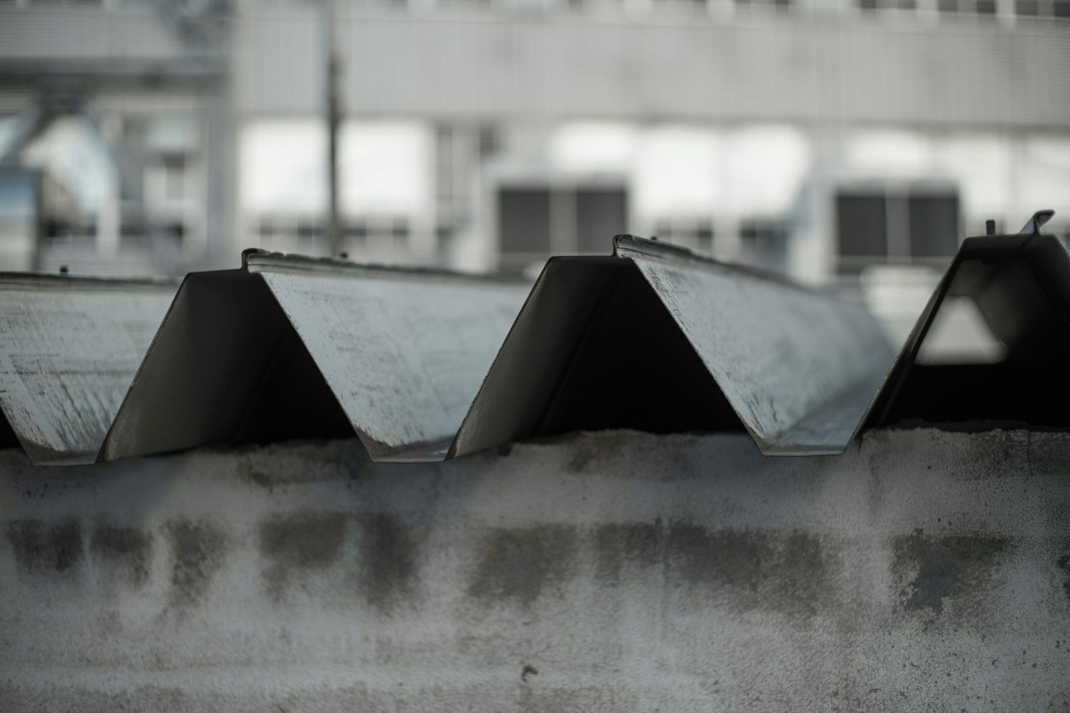 Close-up atap logam bergelombang di depan dinding beton