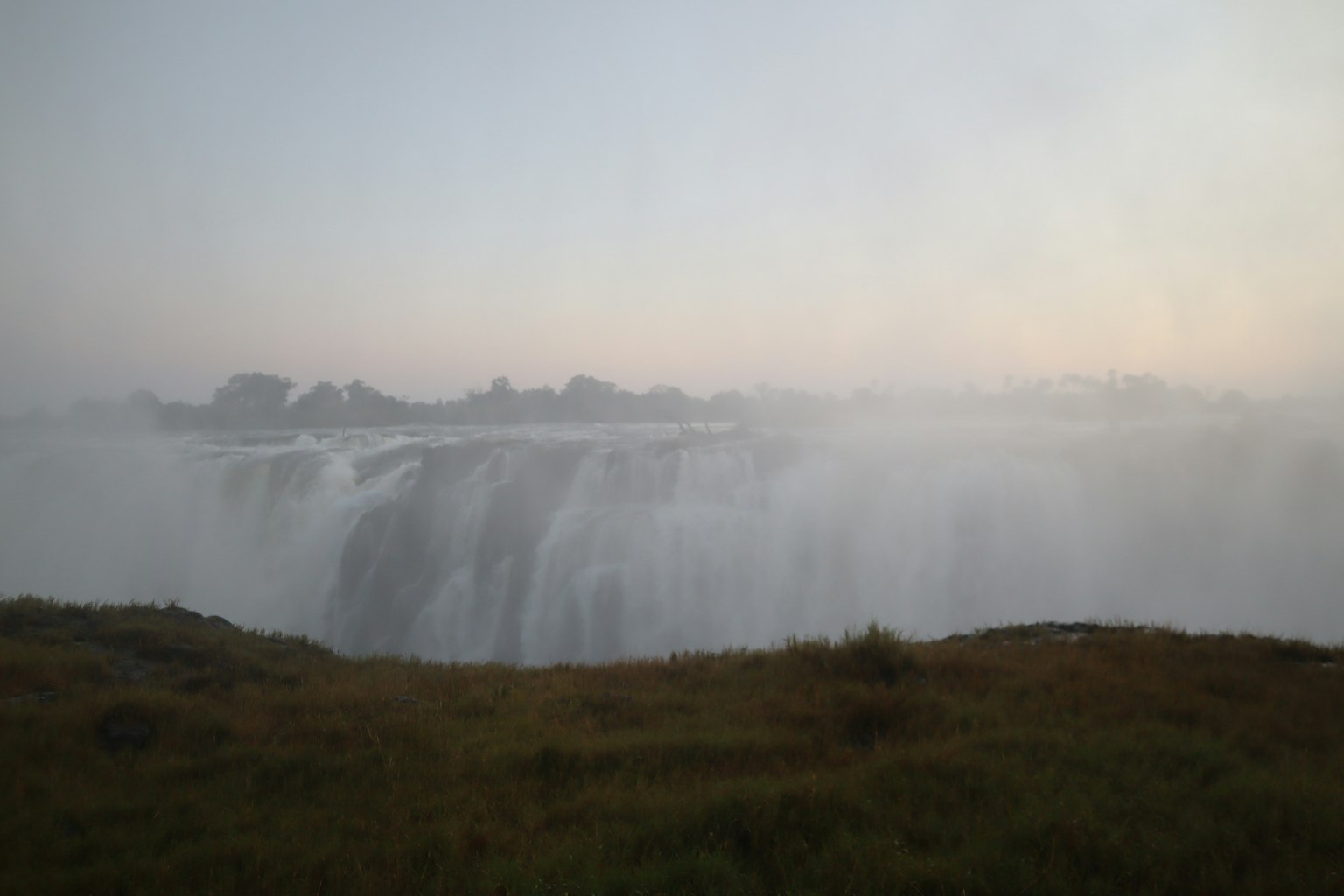 Vista nebbiosa di una cascata con prati circostanti
