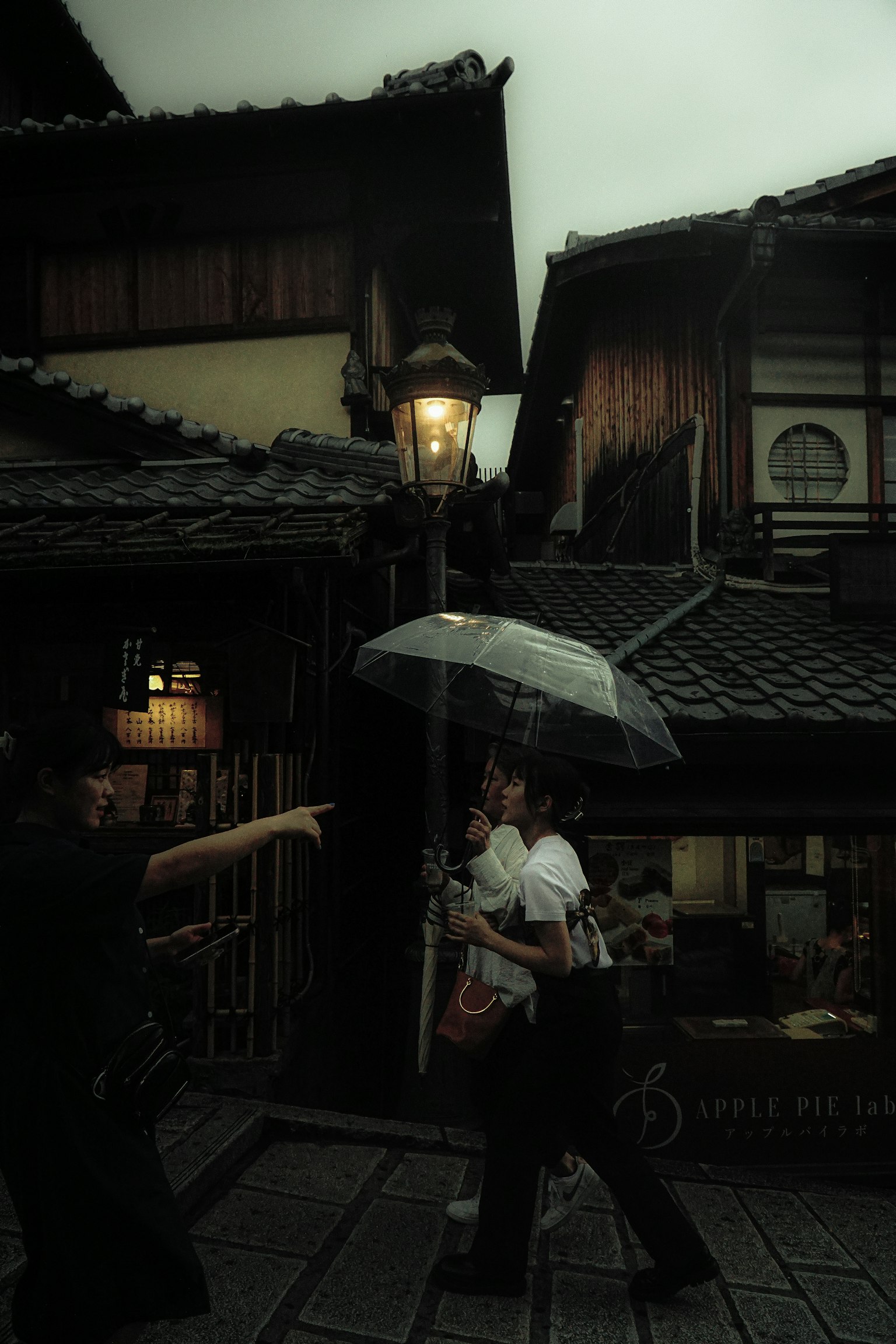 People walking in the rain with an umbrella in a traditional Japanese street scene