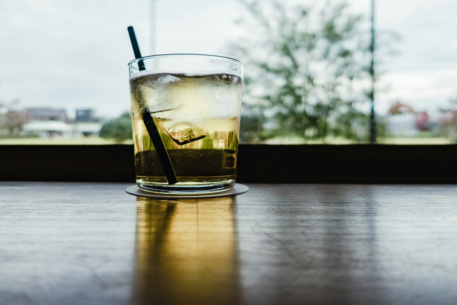窗边木桌上的冰镇鸡尾酒杯
