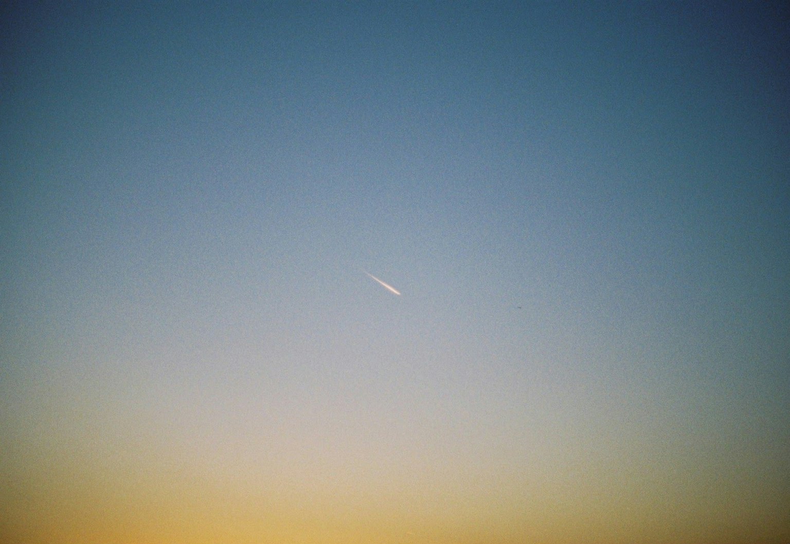 Un hermoso cielo de atardecer con una estela blanca en el fondo azul