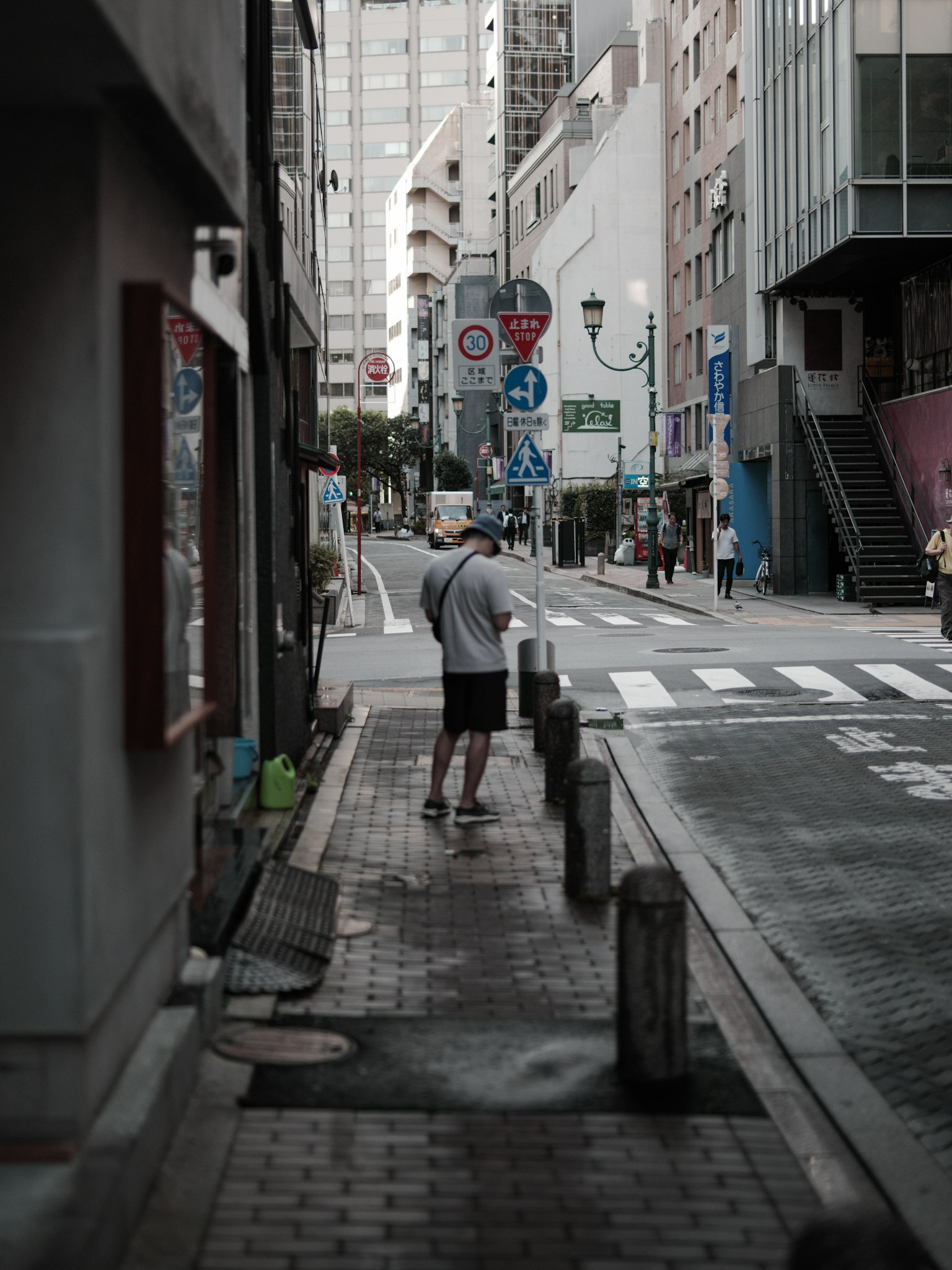 คนยืนอยู่บนถนนแคบๆ ที่มีตึกเรียงรายอยู่สองข้าง