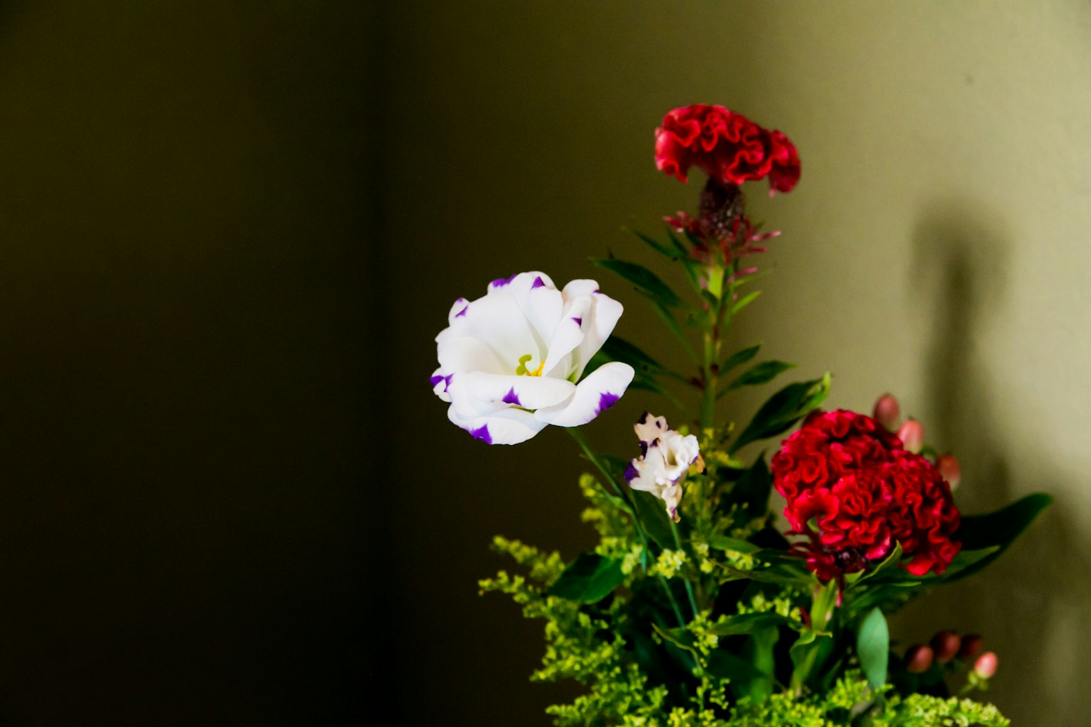Un bouquet avec une fleur blanche et des fleurs rouges dans un vase
