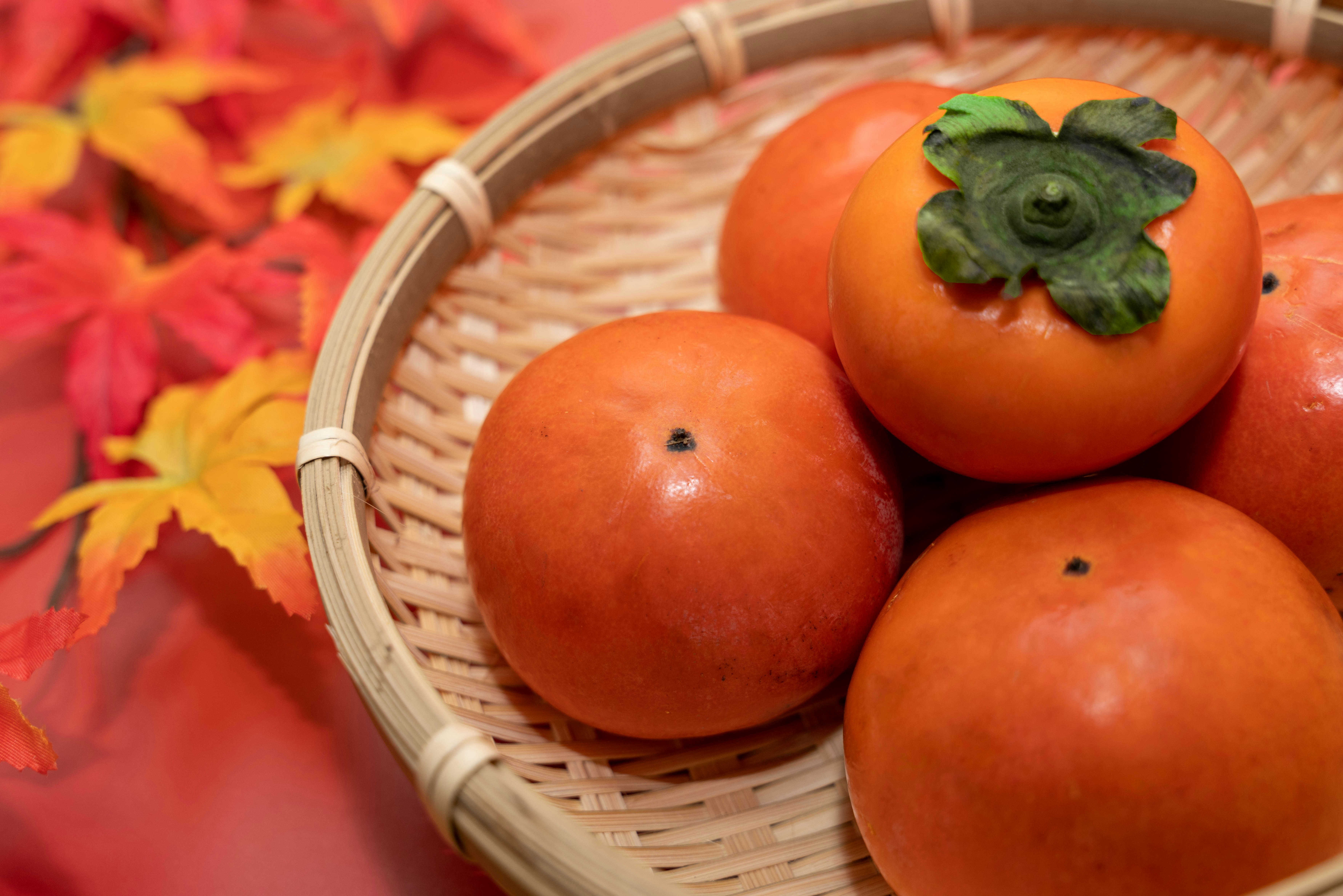 かごに入った柿と紅葉の秋の果物