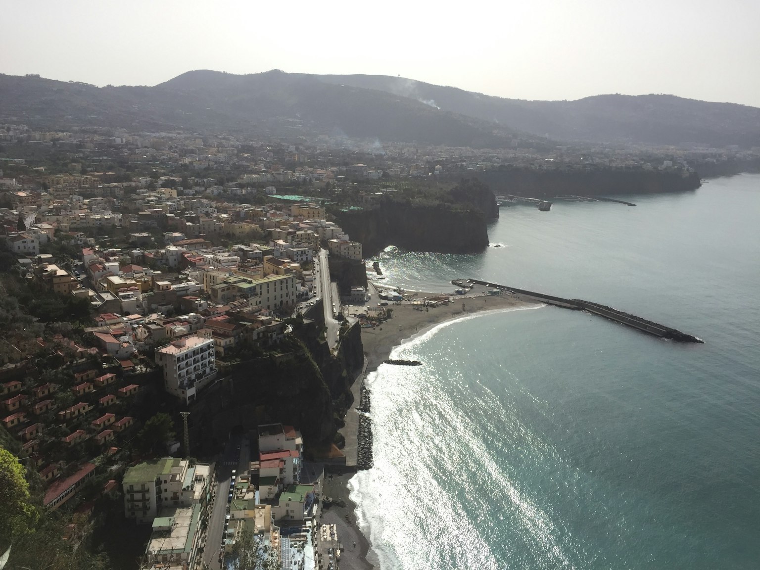 Vista aérea de un pueblo costero con olas y colinas