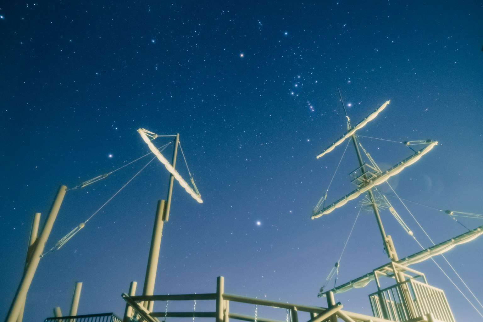 Mâts d'un navire sous un ciel étoilé avec un quai en bois