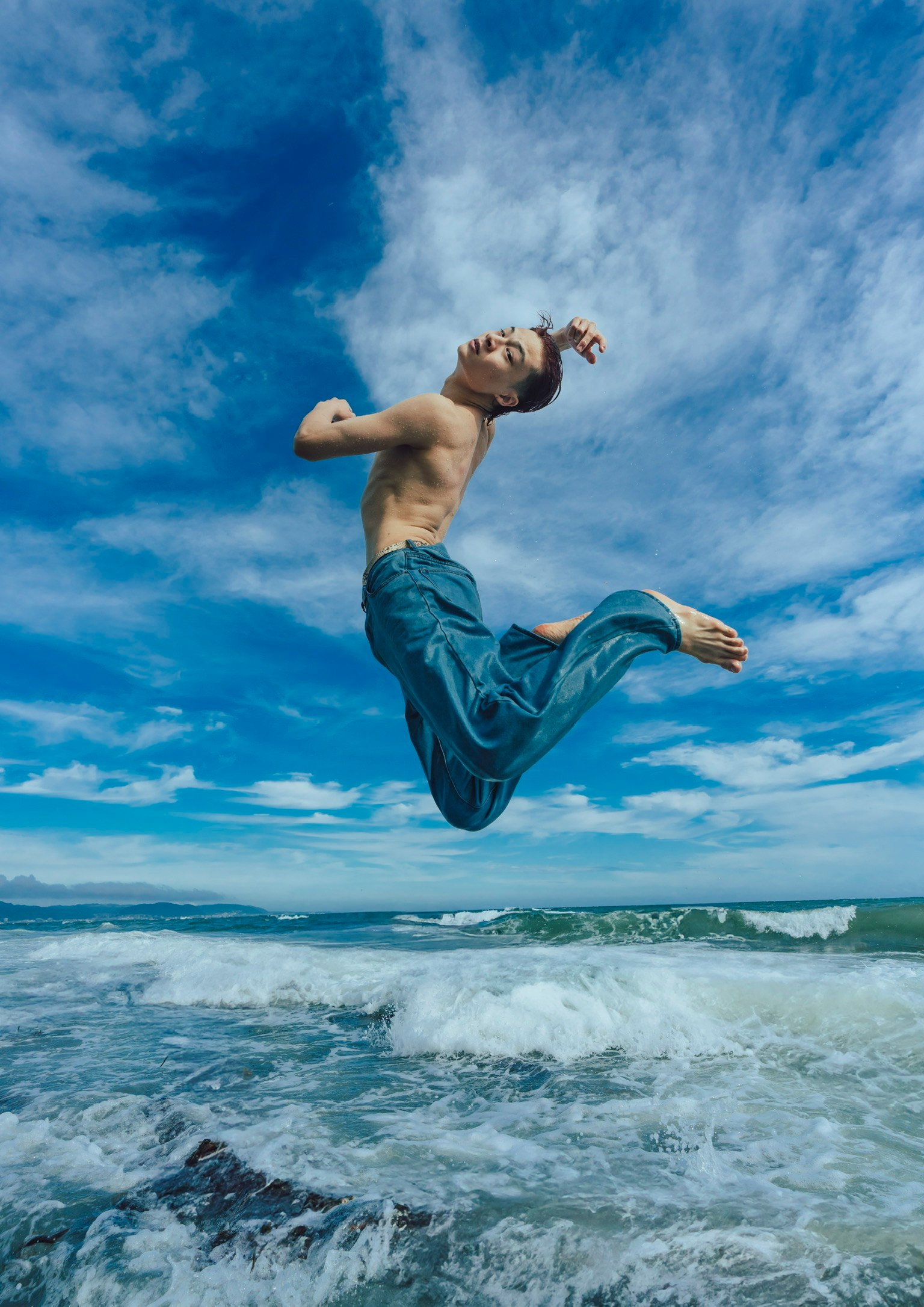海でジャンプする男性の姿 青空と波が背景