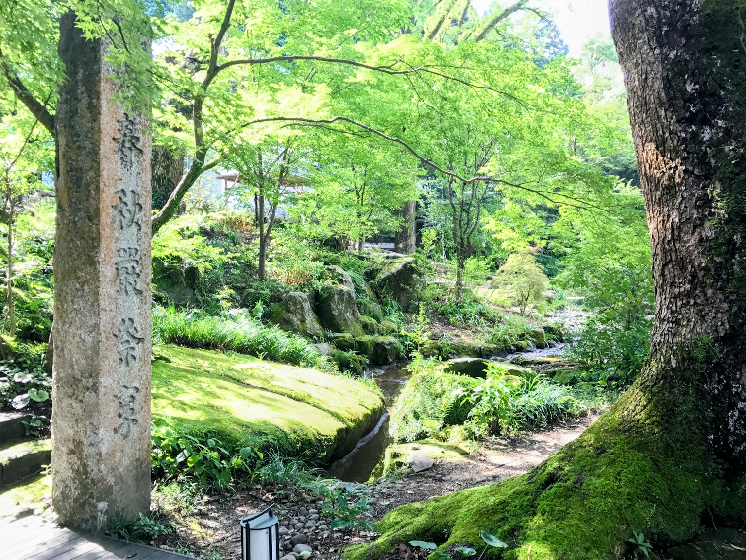 Sentier de jardin luxuriant avec un monument en pierre et une verdure vibrante
