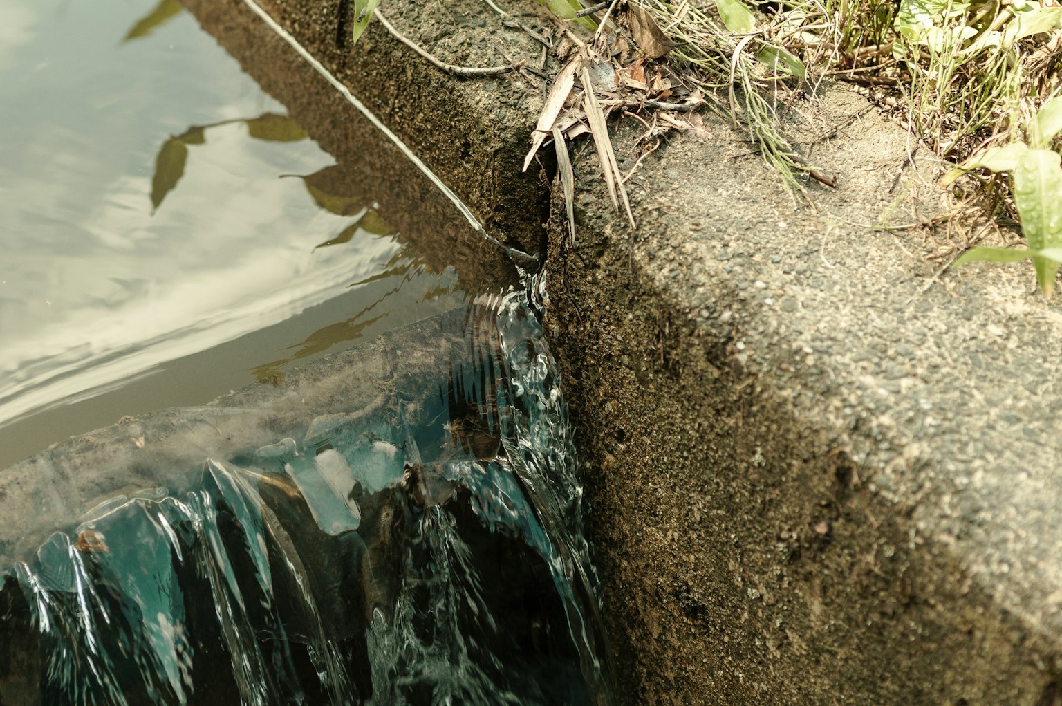 Primer plano de agua fluyendo contra un borde de concreto