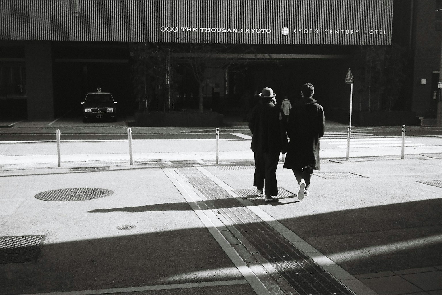 兩個人穿著黑色外套在城市街道上行走