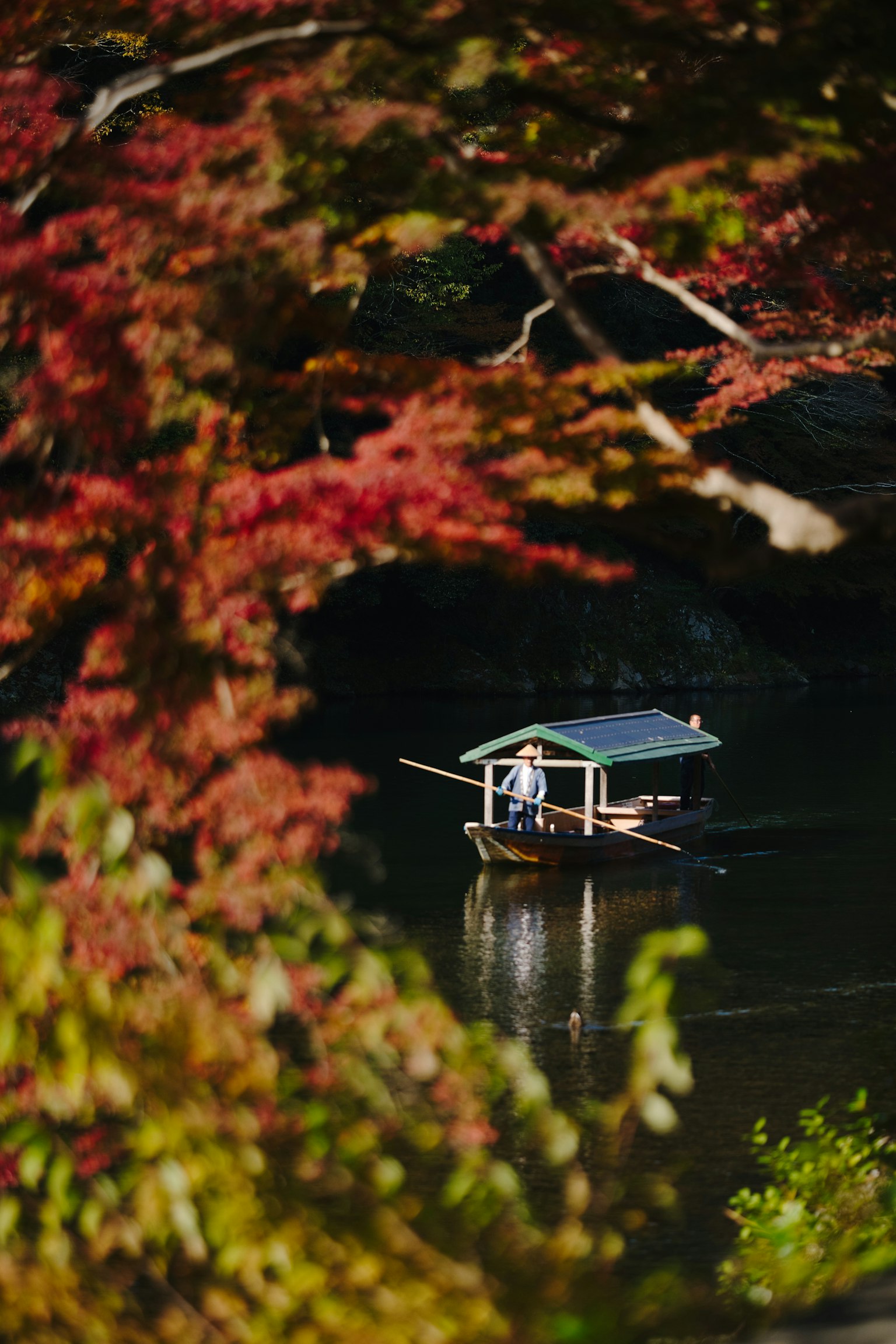 秋の紅葉に囲まれた小舟が静かな水面を漂う風景