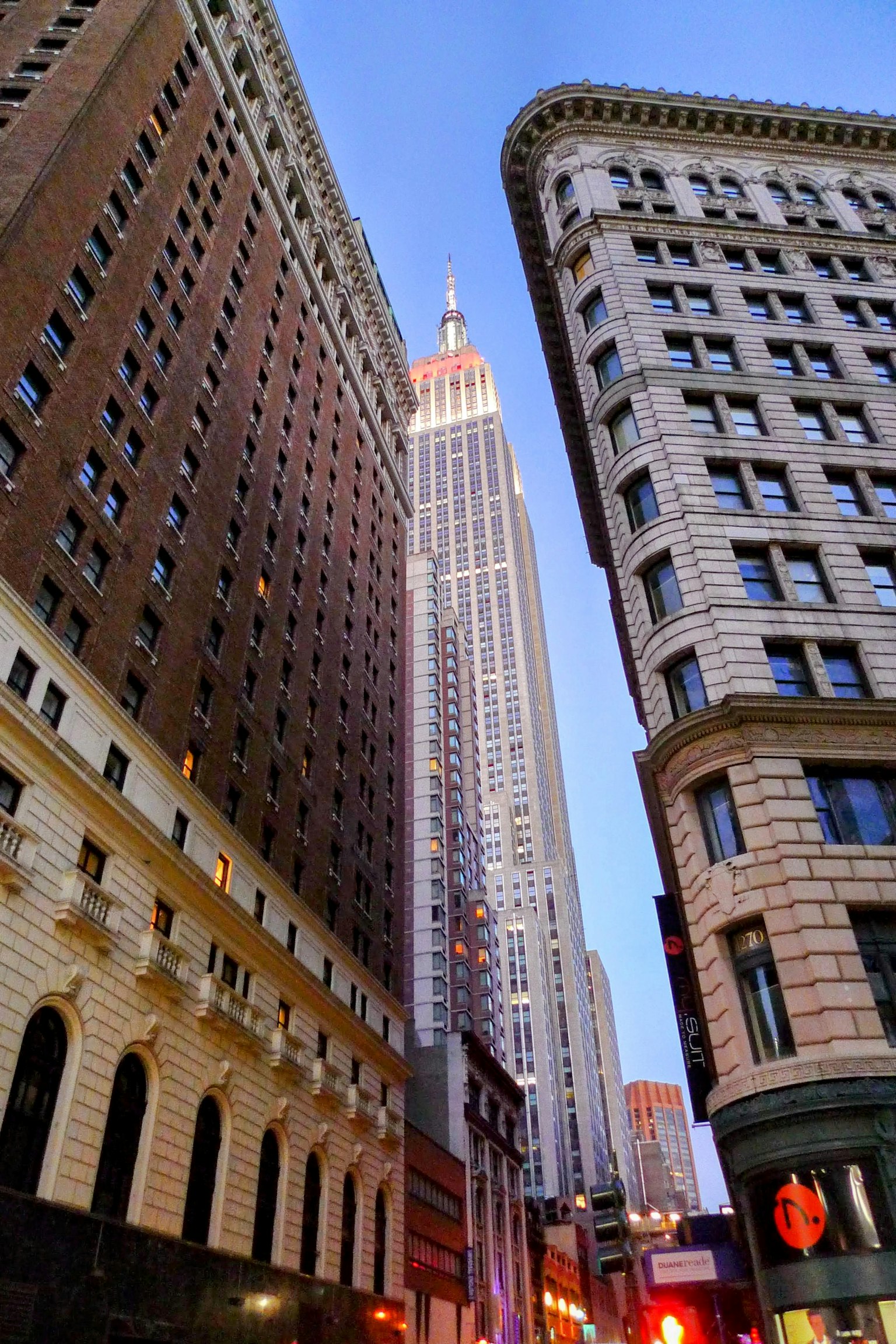 View of Empire State Building between tall buildings