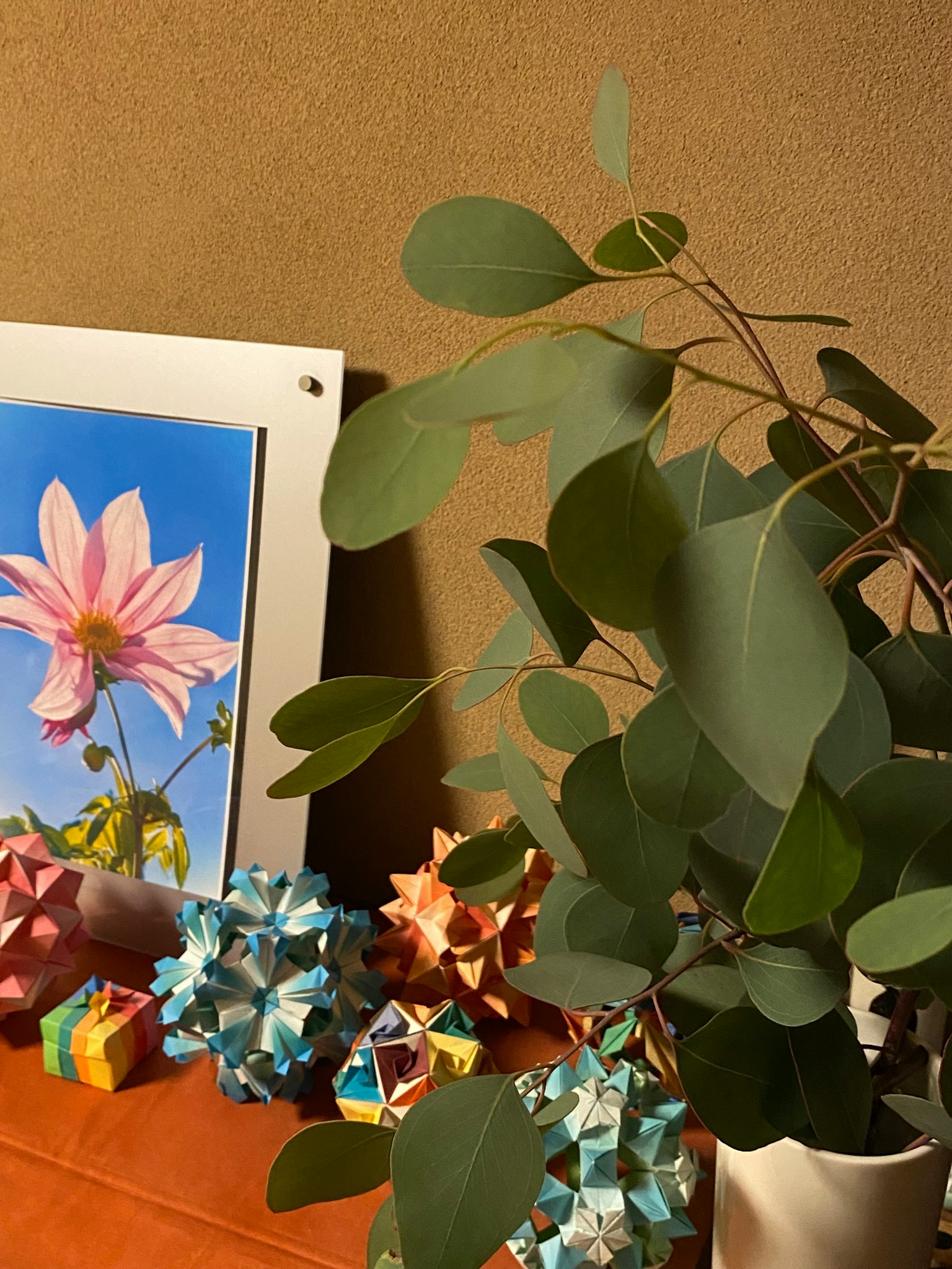 Foglie di pianta accanto a un'esposizione di origami colorati e a un dipinto floreale