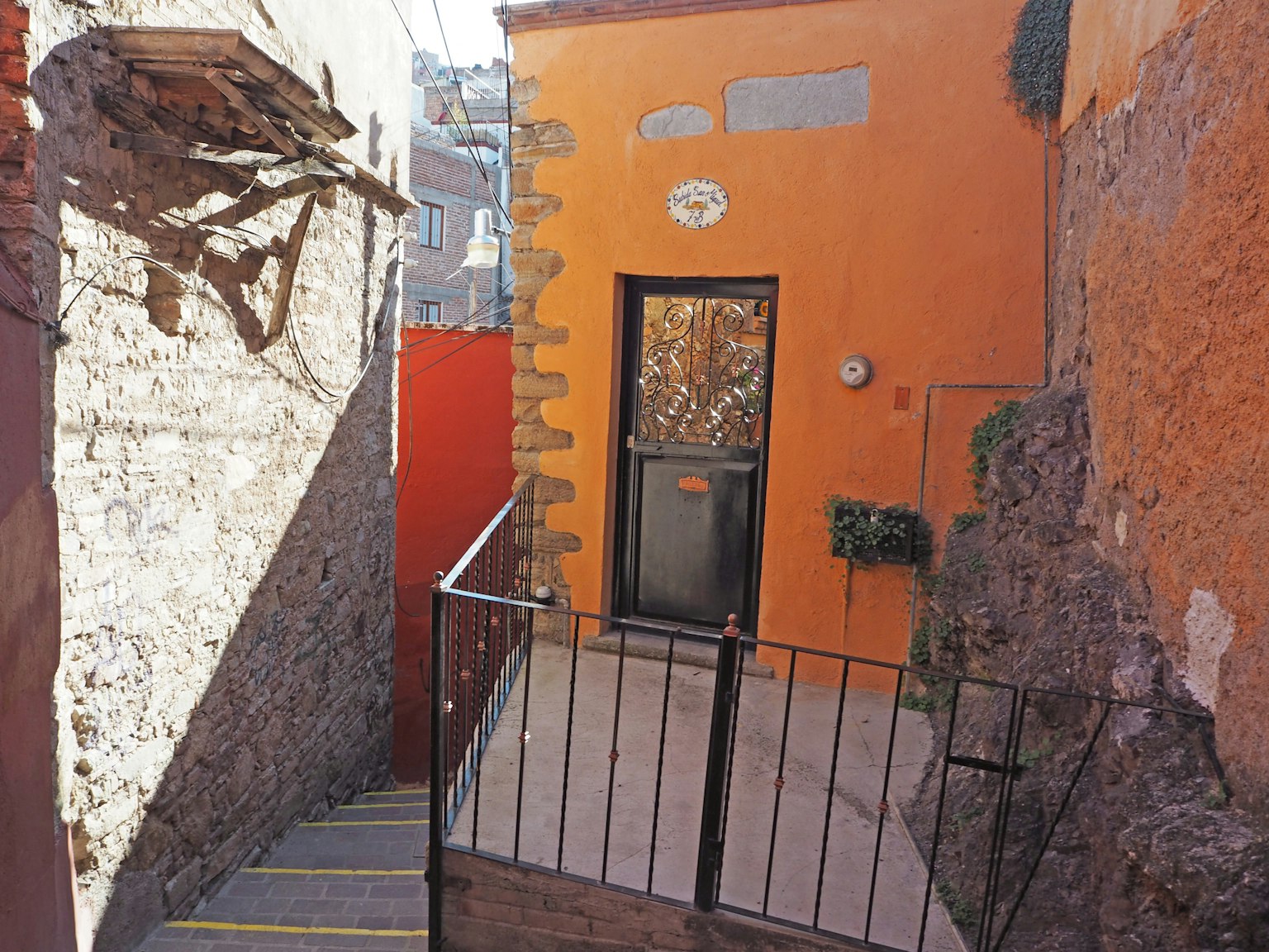 Scena di strada stretta con una casa arancione e scale