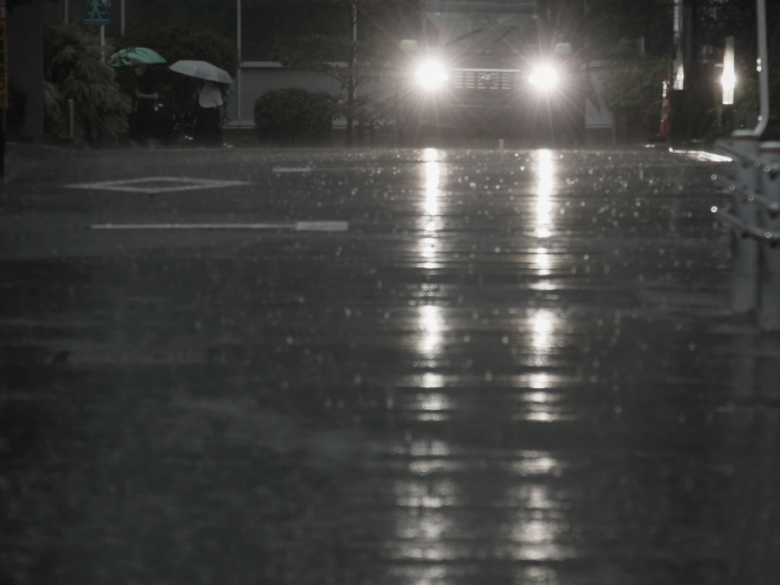 Car headlights reflecting on a wet street during rain