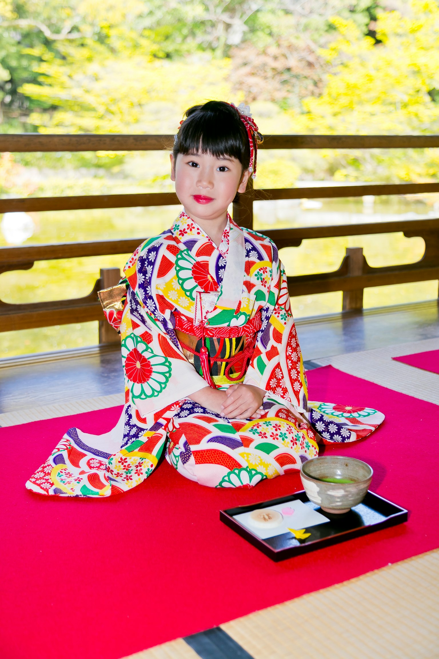 Một cô gái trong bộ kimono đầy màu sắc ngồi trong một khu vườn Nhật Bản xinh đẹp chuẩn bị cho buổi lễ trà