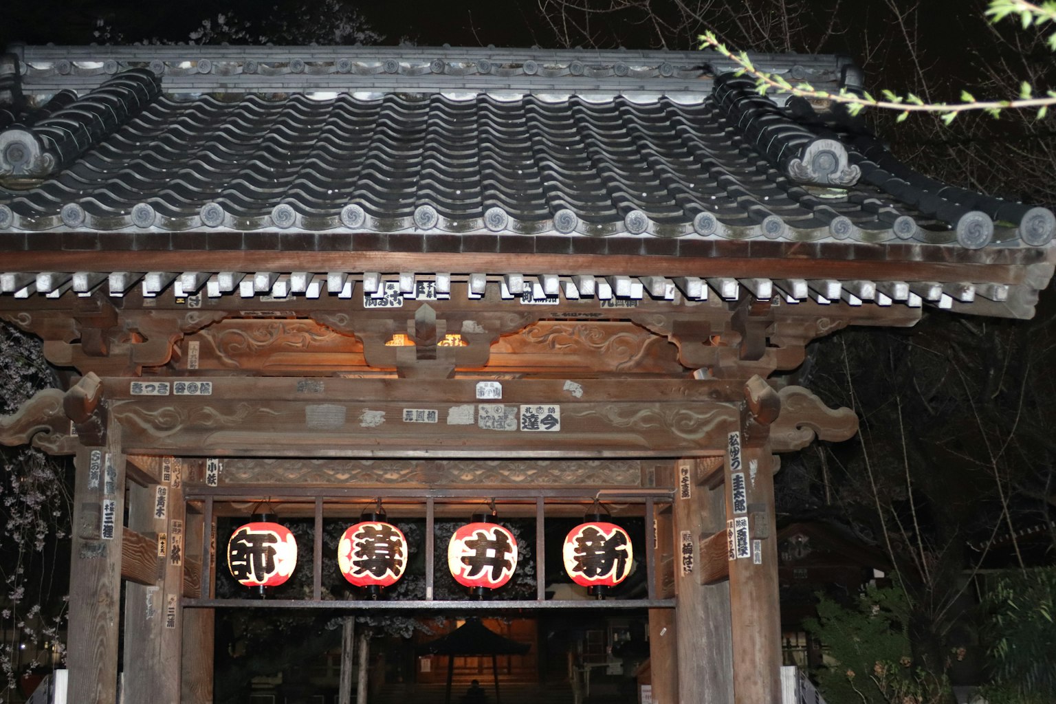 夜間傳統日本大門的圖像，特點是古老的木結構和瓦屋頂，明亮的照明