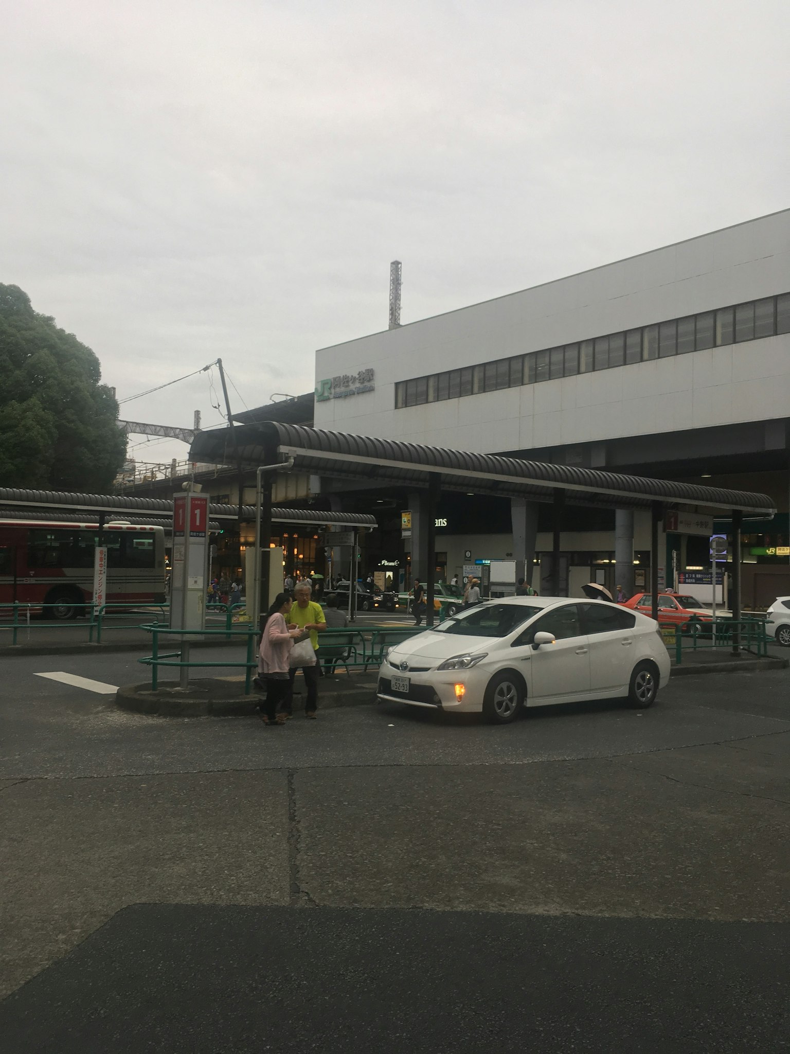 Ein weißes Auto fährt durch eine Kreuzung in der Nähe eines Bahnhofs