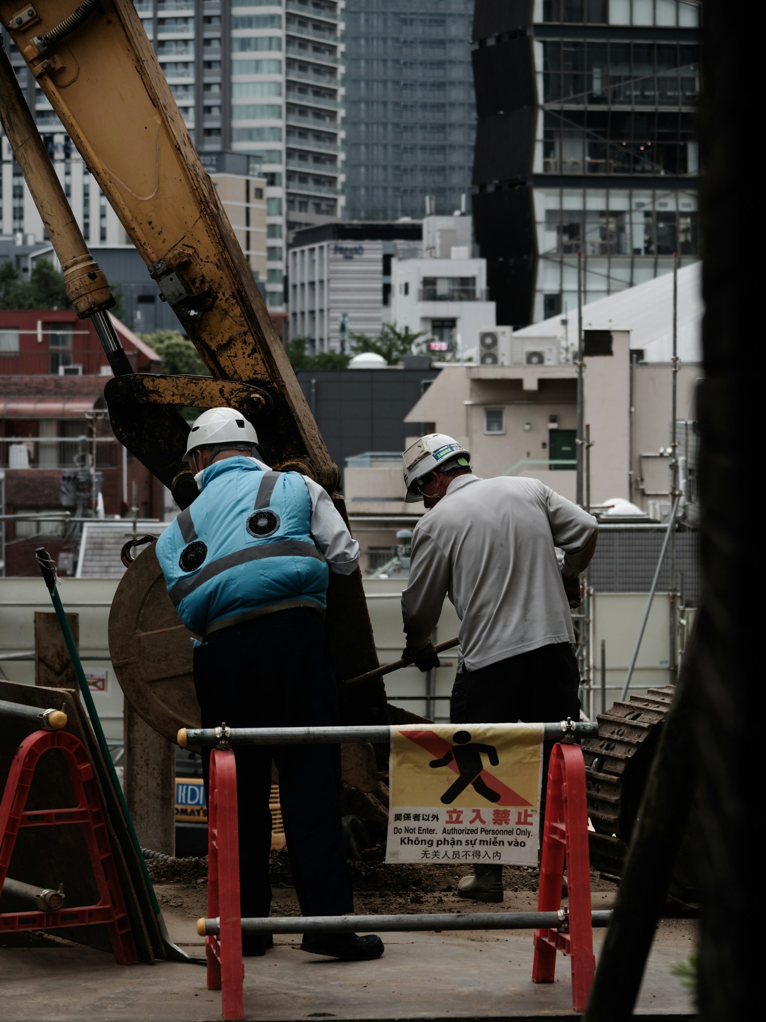 两个在建筑工地工作的工人穿着安全帽和安全背心
