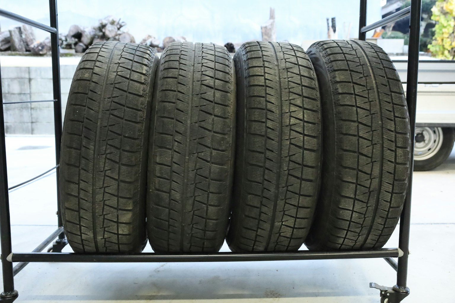 Four black tires neatly stacked on a rack