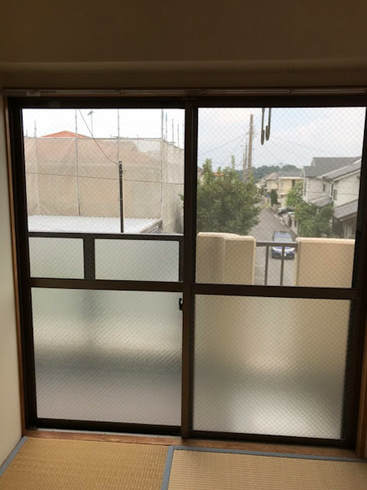 Interior view of a room with frosted glass windows overlooking residential buildings