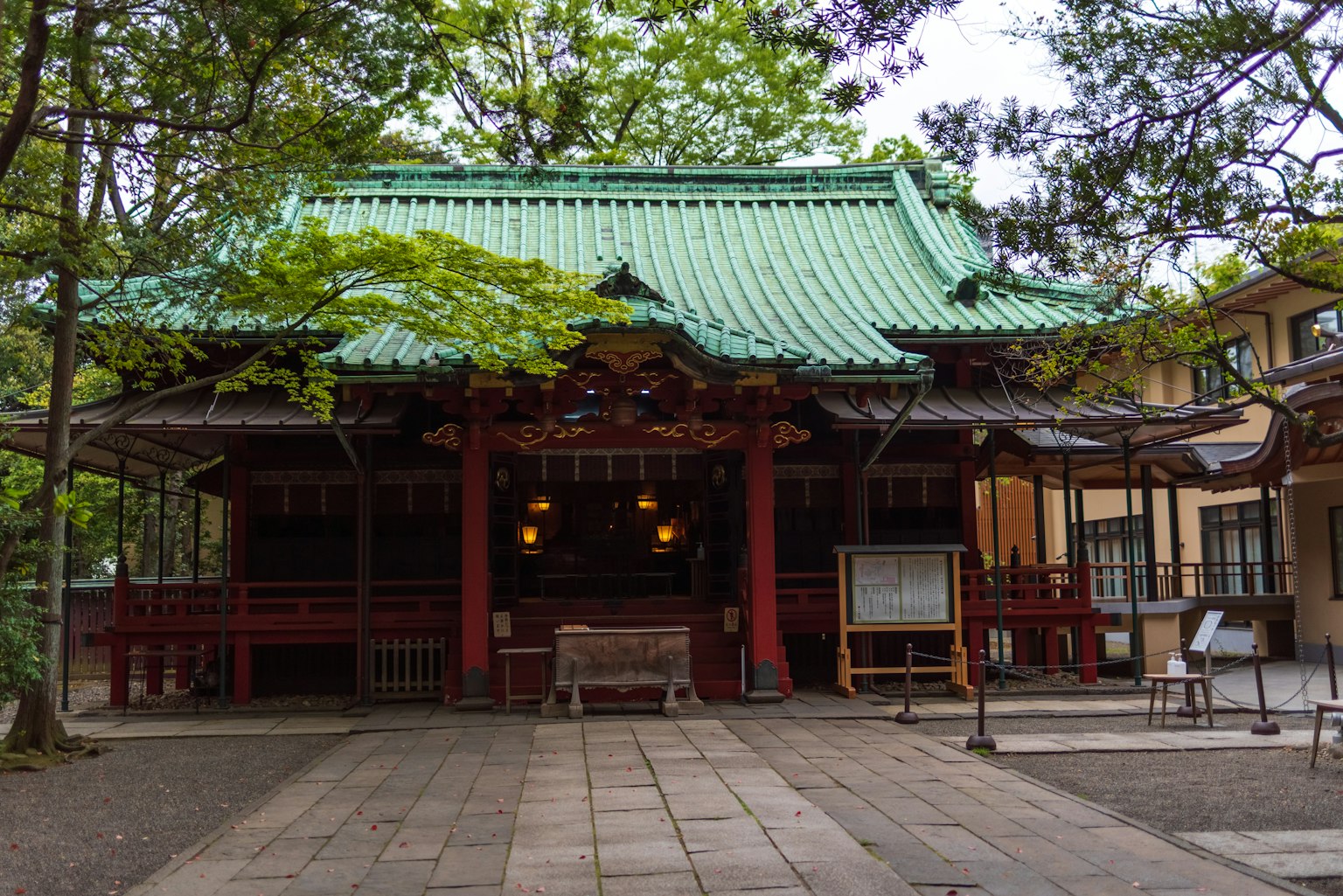 Shrine building with a green roof surrounded by trees