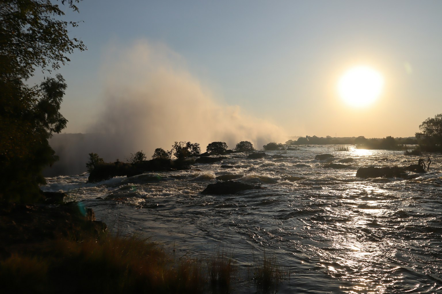 Vista panoramica di un fiume con un tramonto splendente e nebbia che si alza