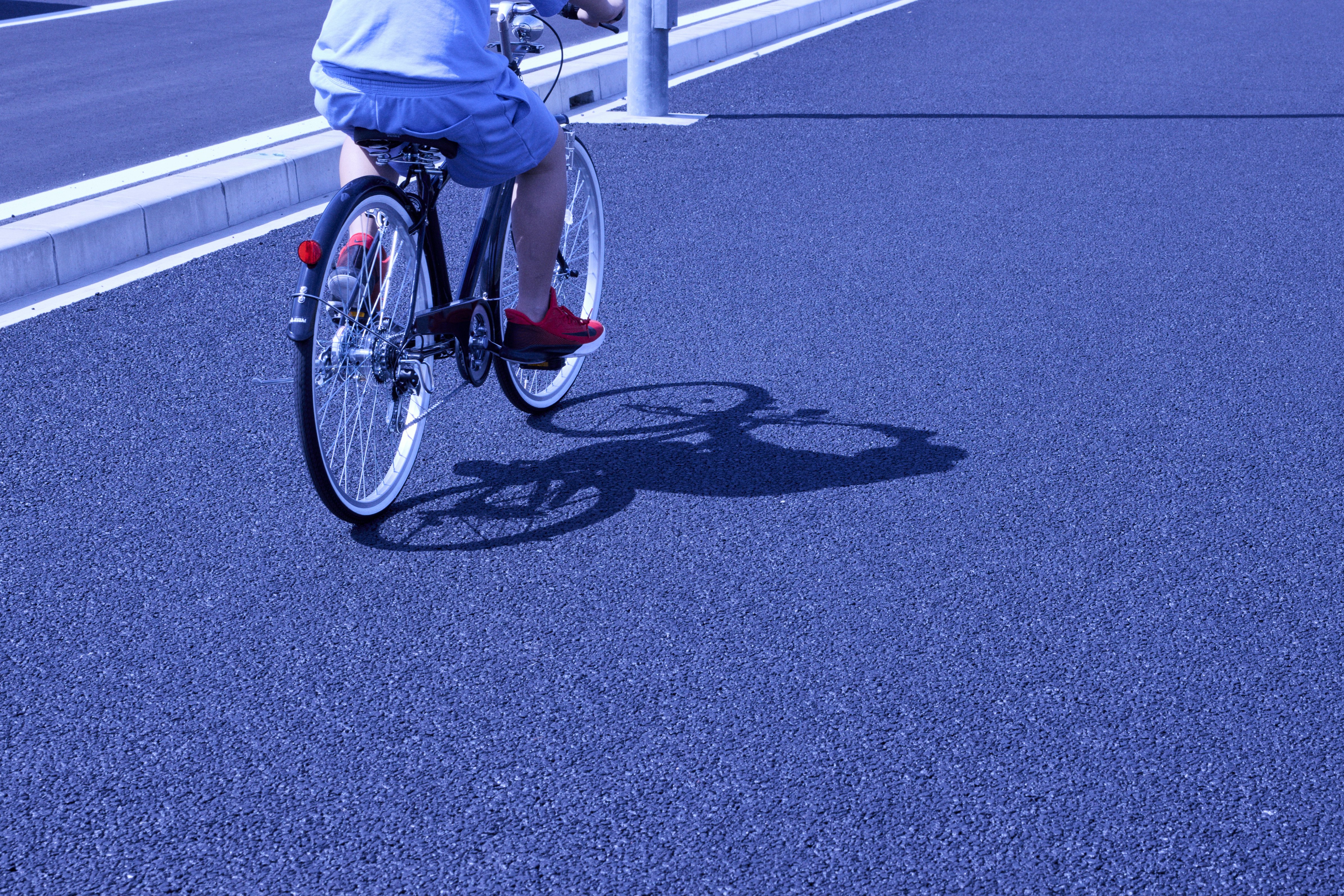 青い自転車レーンを走る自転車のある路面