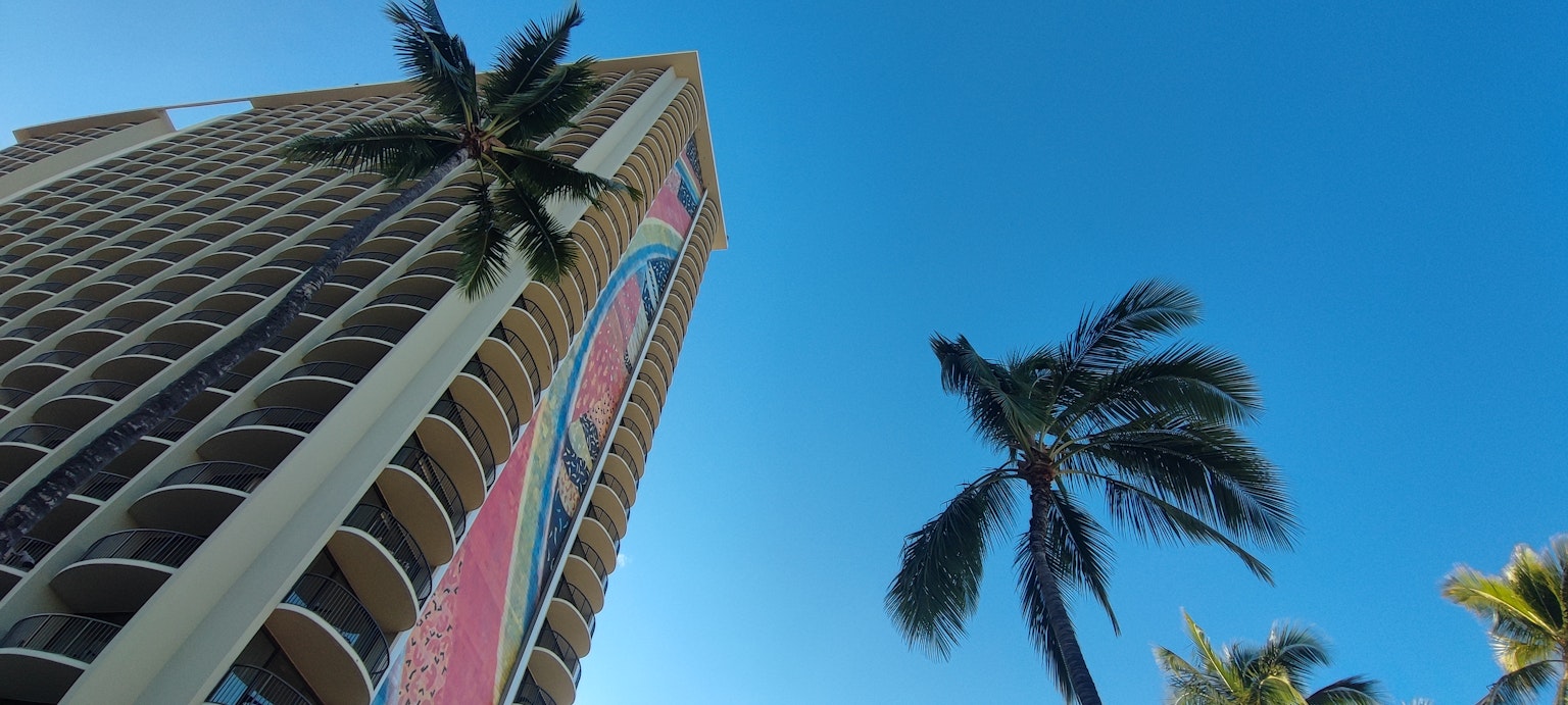 Edificio alto con palmeras contra un cielo azul