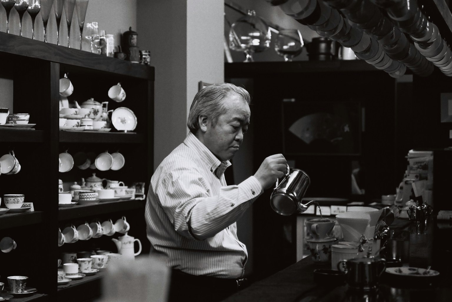 Uomo anziano che versa caffè in un caffè vintage