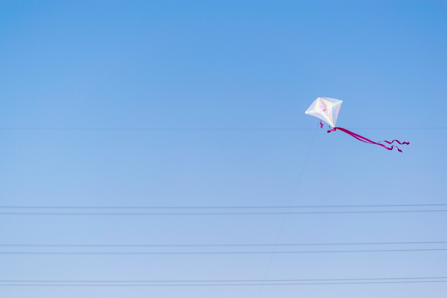 Ein weißer Drache schwebt in einem blauen Himmel mit roten Bändern