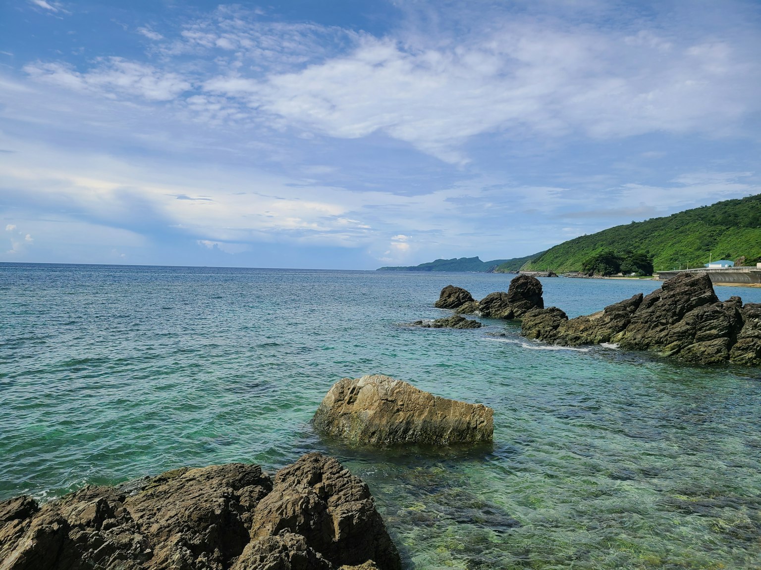 Pemandangan indah laut biru dan bukit hijau
