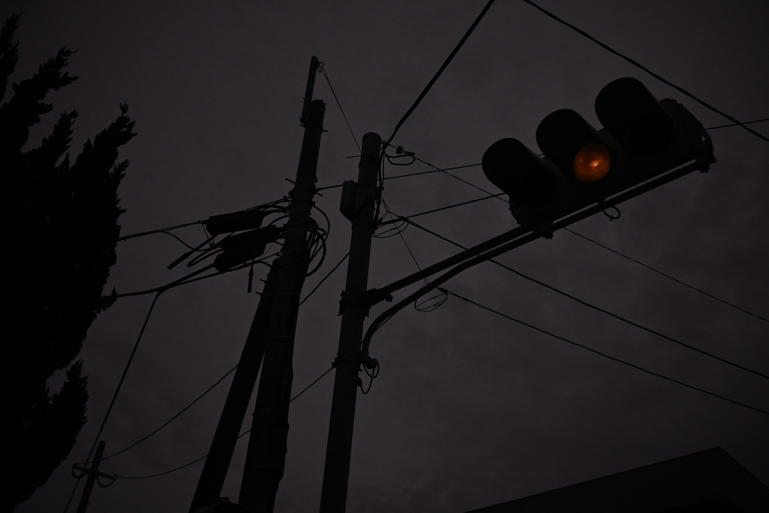 Silhouette tiang listrik dan lampu jalan melawan langit senja