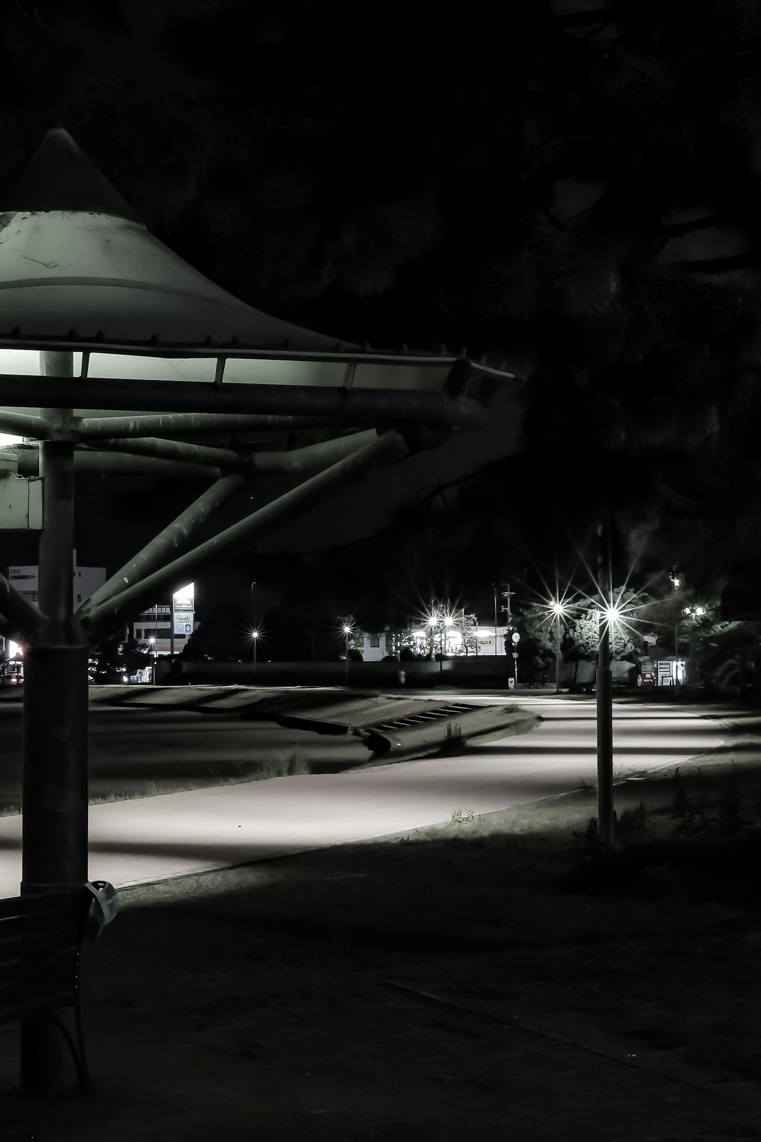 Vista nocturna de un parque con iluminación y estructura de pabellón