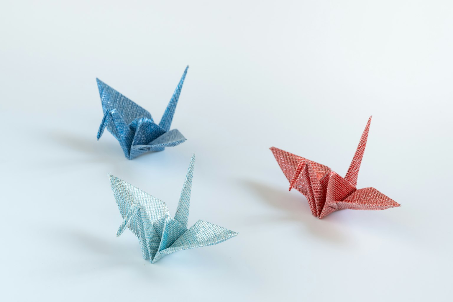 Ba con hạc origami màu xanh và đỏ trên nền đơn giản