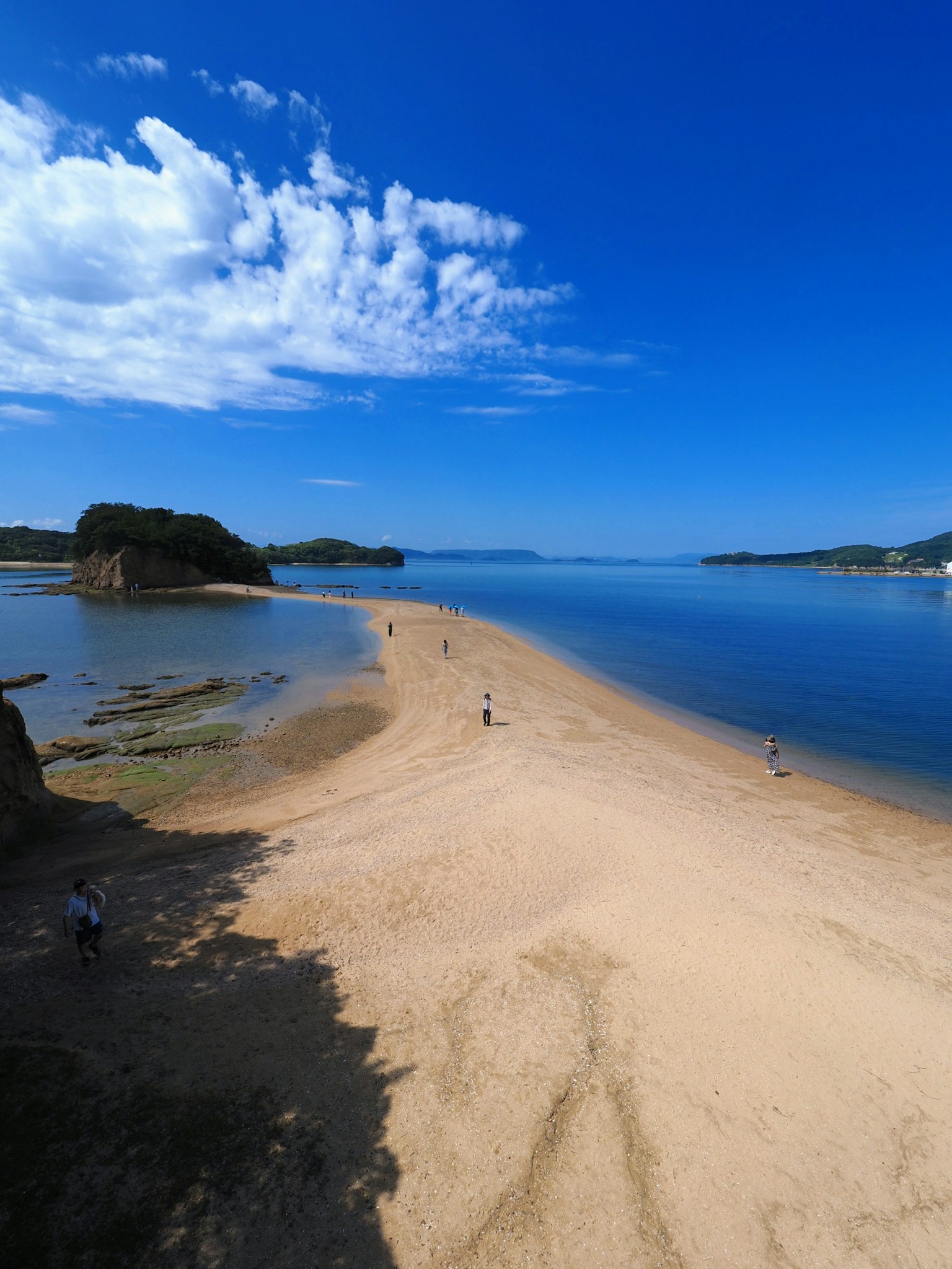 Scenic view of a sandy beach surrounded by blue skies and calm waters