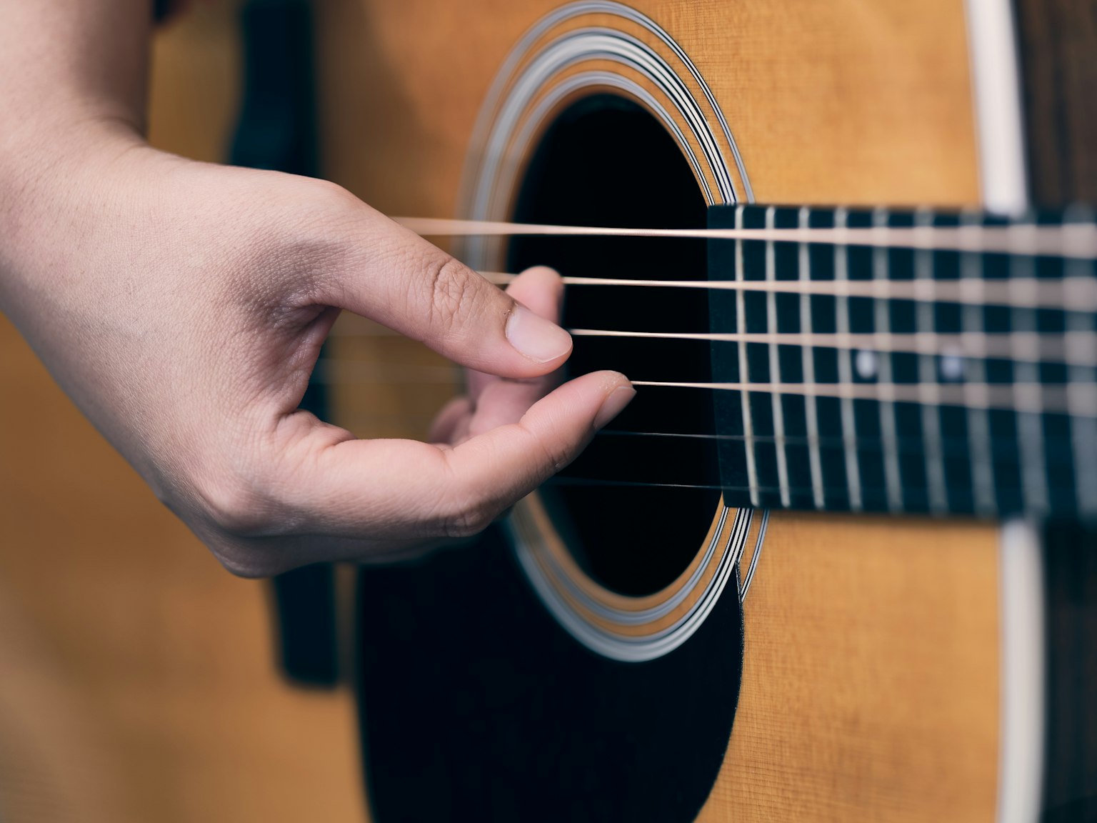 Bàn tay đang gảy dây của một cây guitar acoustic