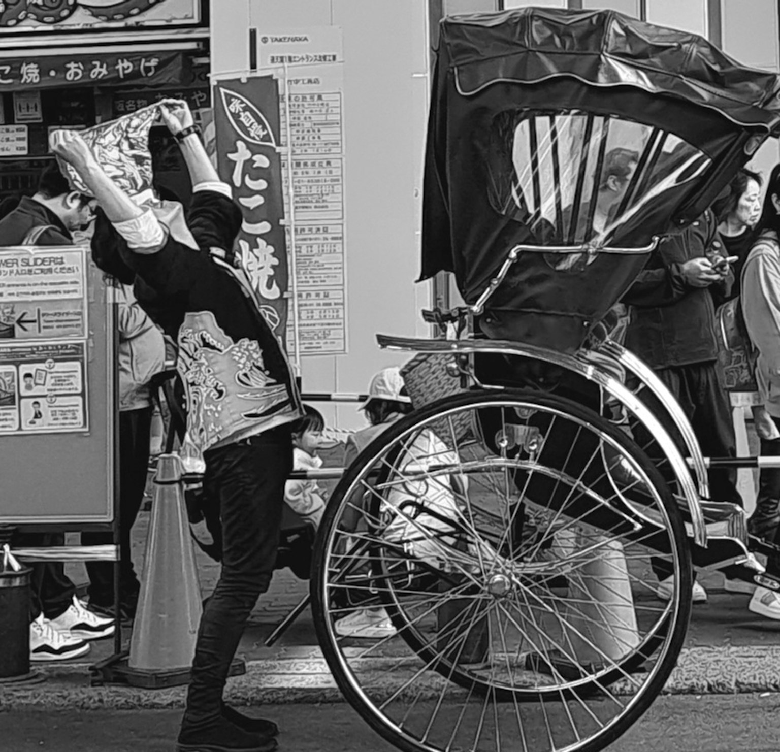 Foto in bianco e nero di un uomo che posa davanti a un rickshaw